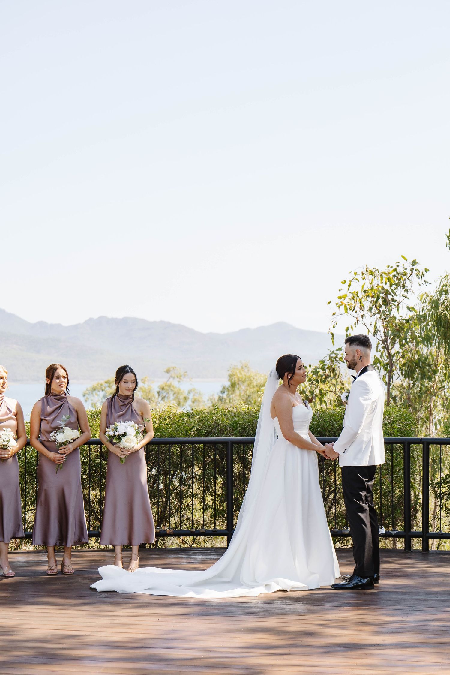 Outdoor wedding ceremony on a mountain viewpoint with bridal party in lavender dresses.