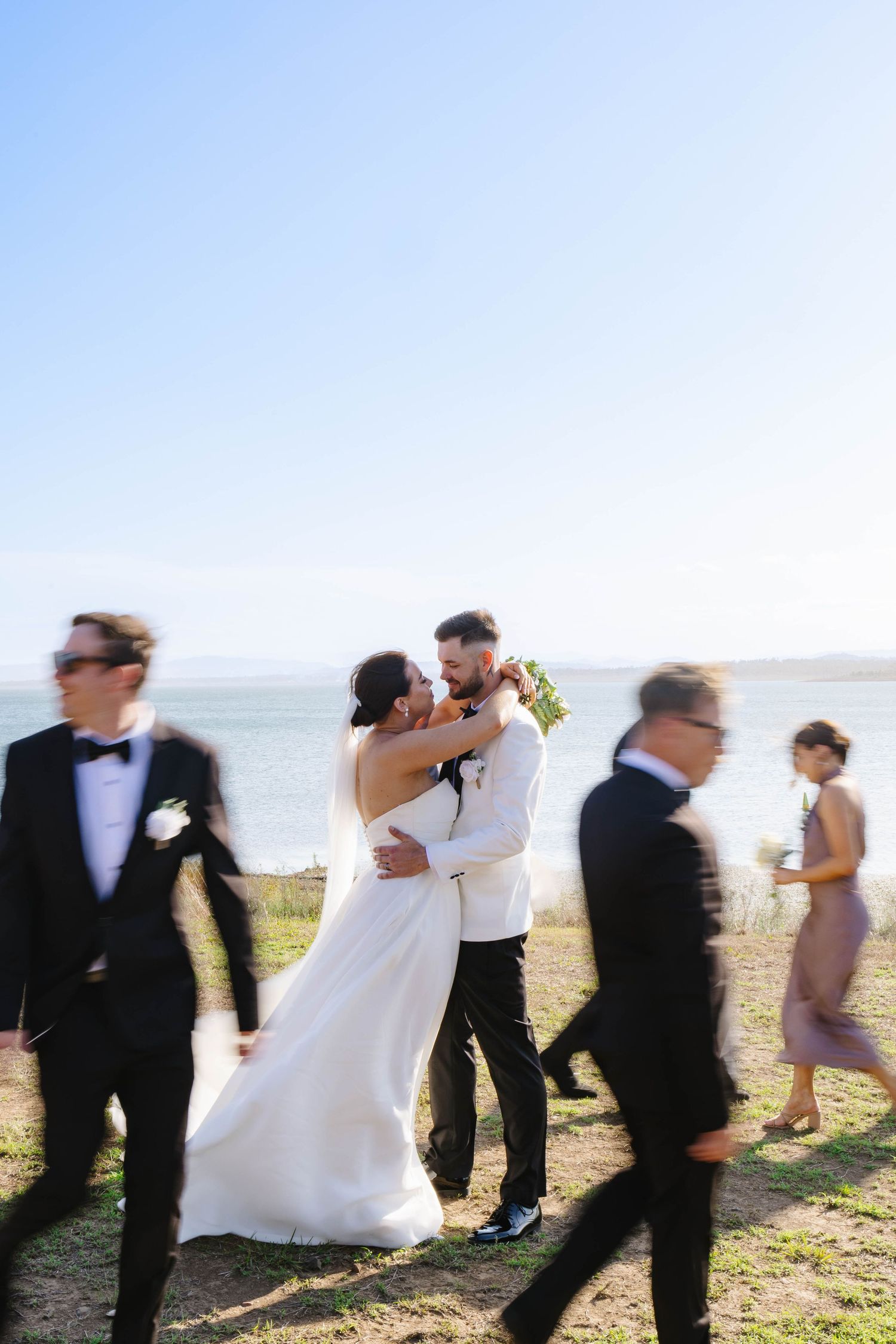 Wedding party members walking and celebrating on a sunny hillside.