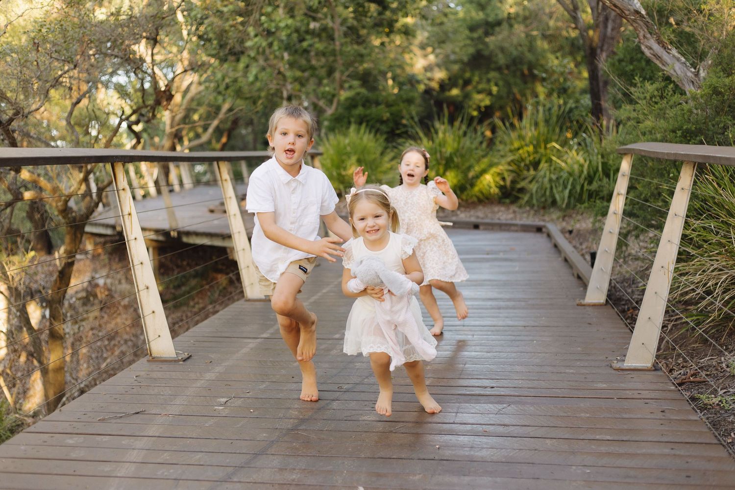 Family walking together on a wooden boardwalk surrounded by lush greenery.
