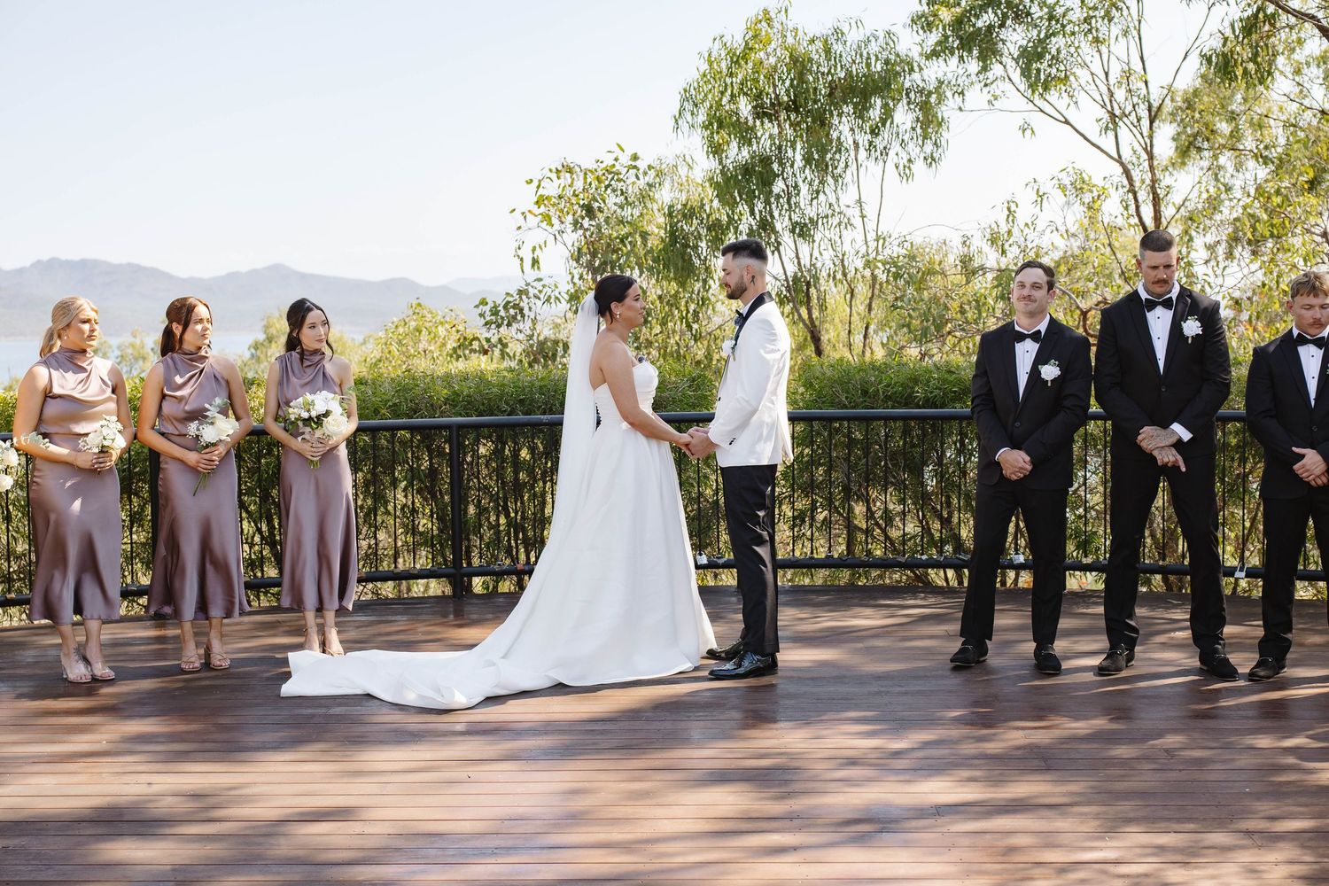 Wedding party members walking in formation along an outdoor path.
