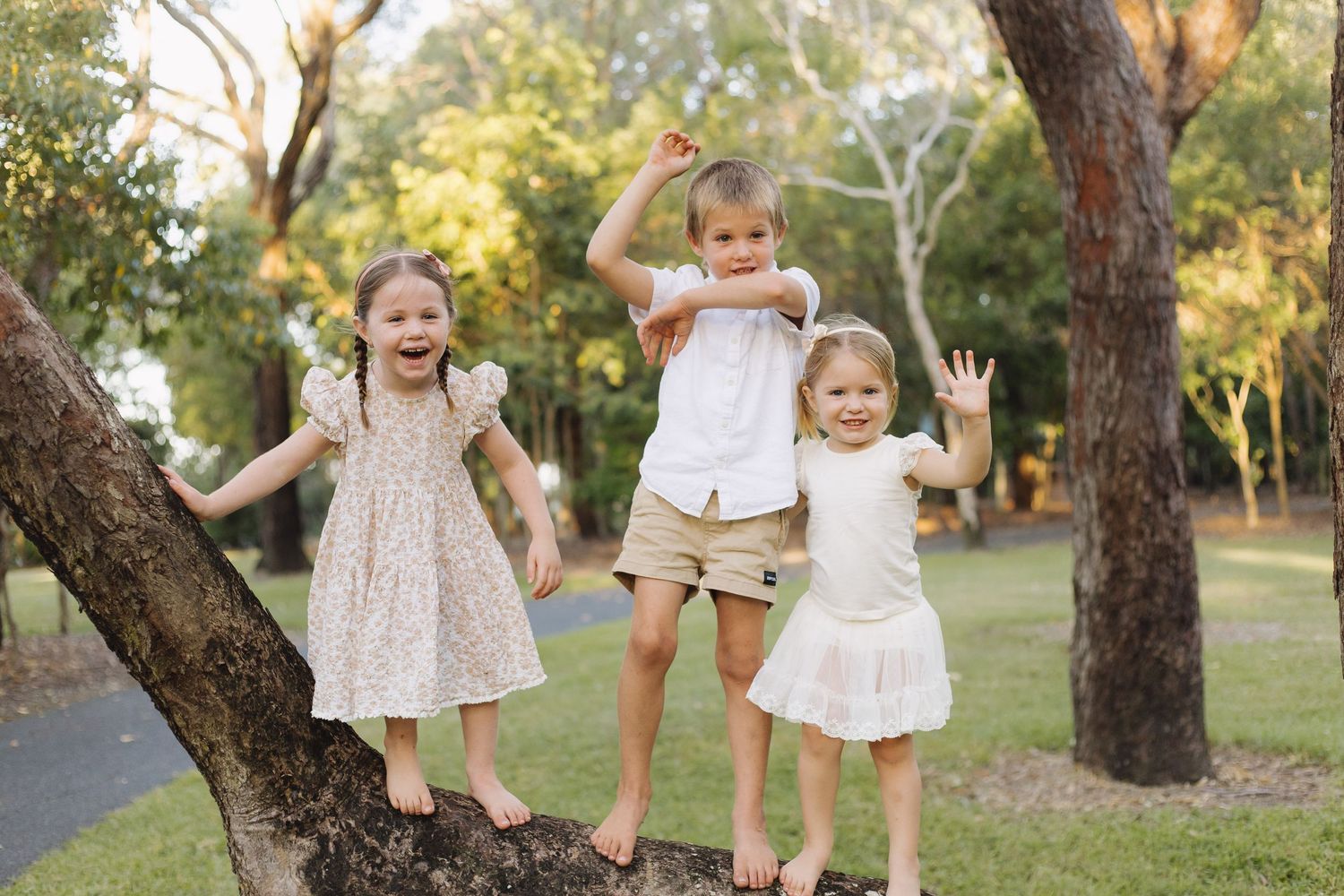 Children playing and laughing together under trees in a park setting.