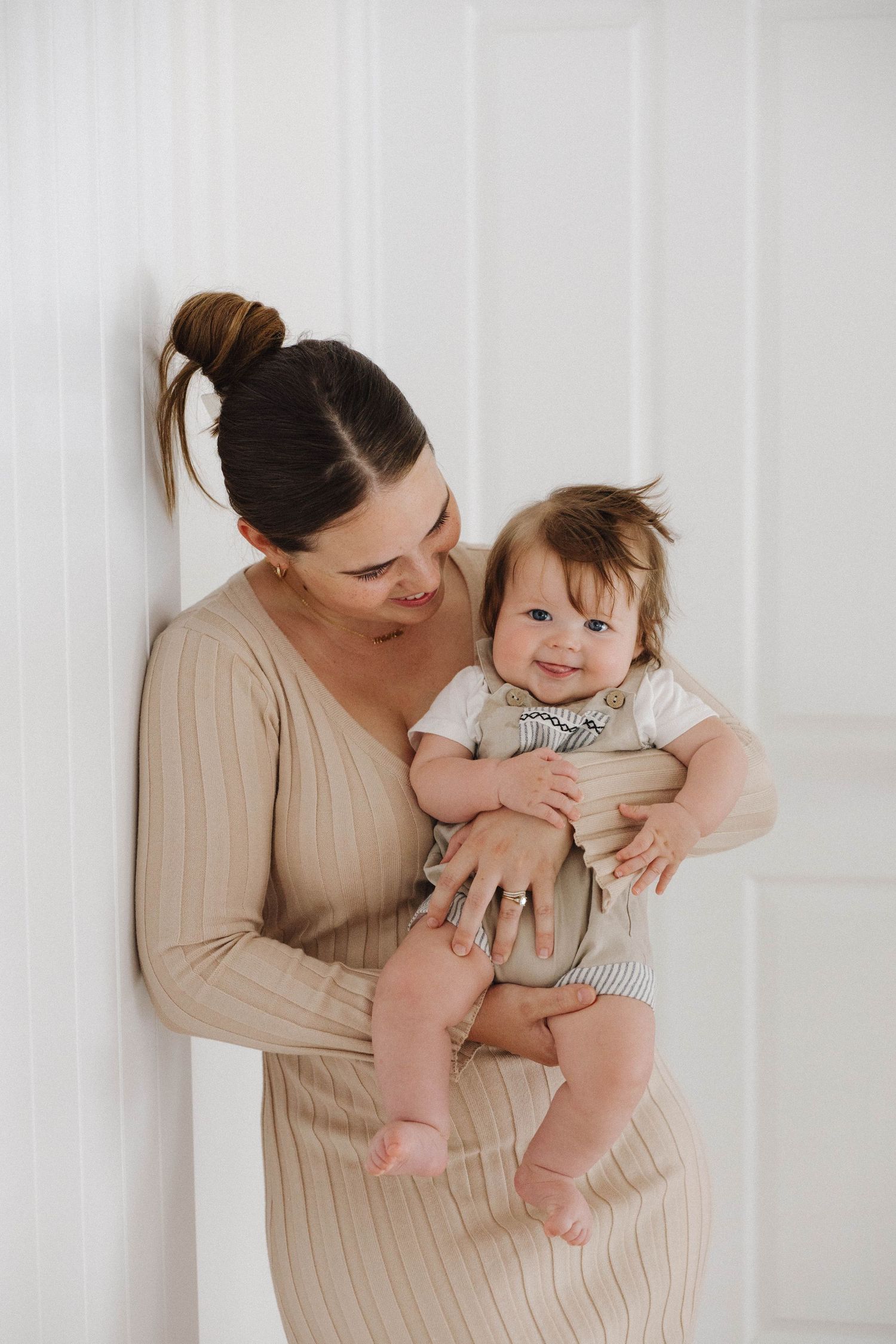 Sweet bonding moments between parent and baby in a bright white room.