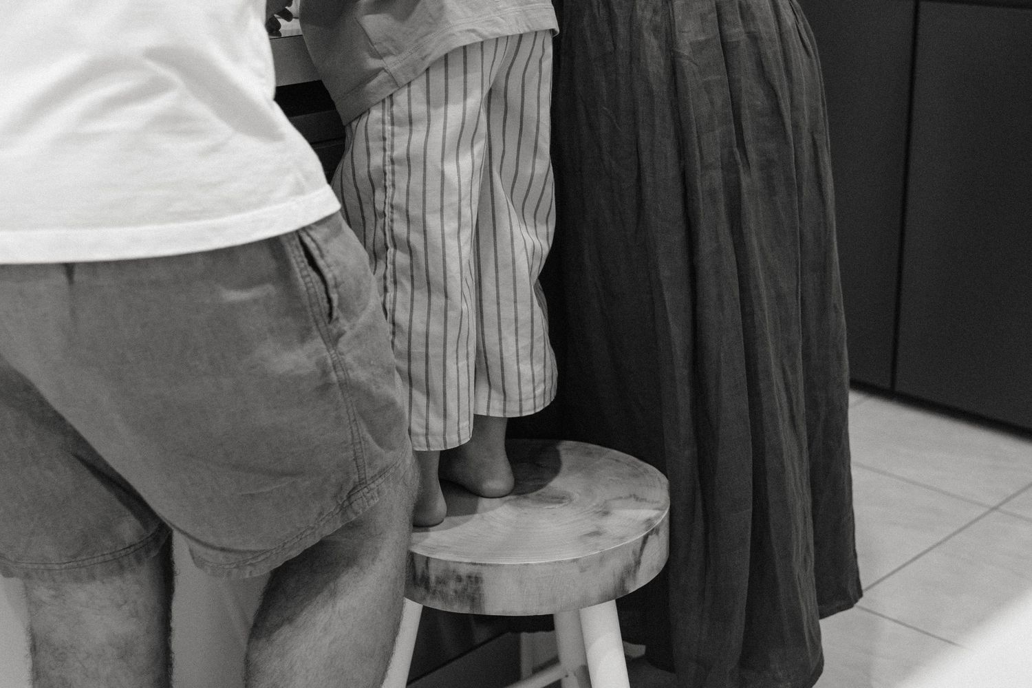Group of people in casual attire standing together in a kitchen.