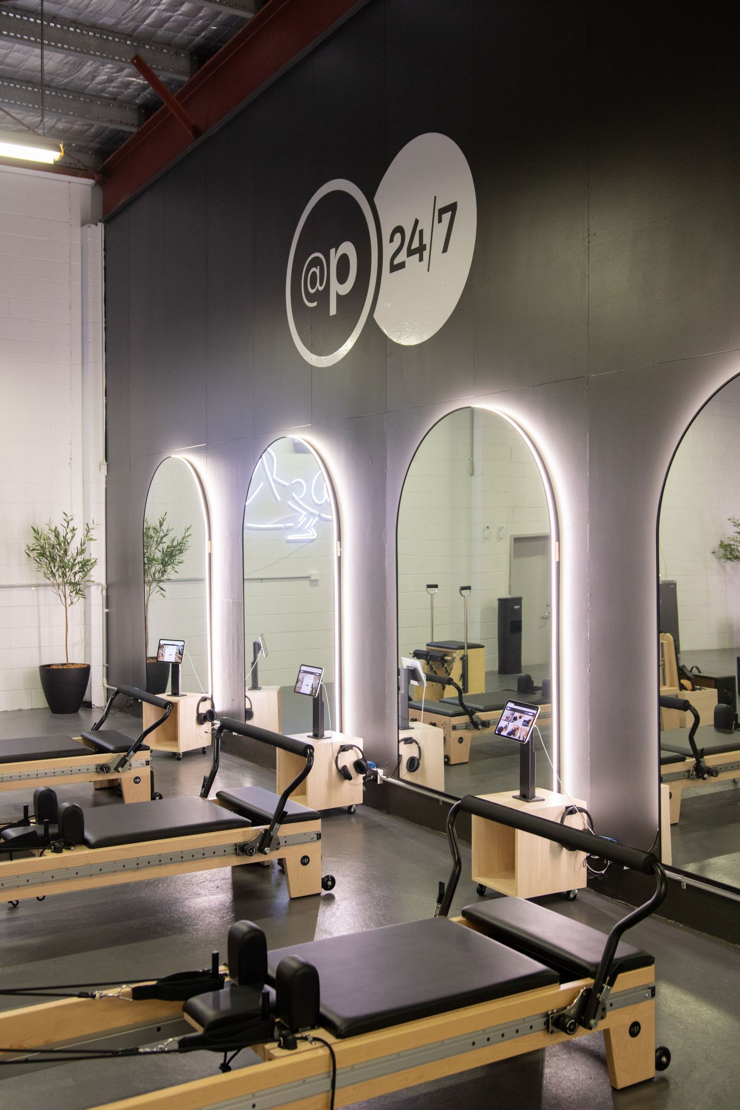 Modern fitness studio with illuminated arches and multiple pilates reformer machines.