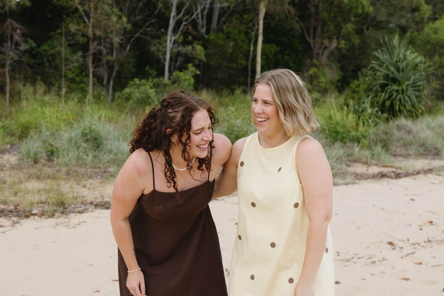 Couple embraces in casual outfits during an outdoor photoshoot with natural lighting.