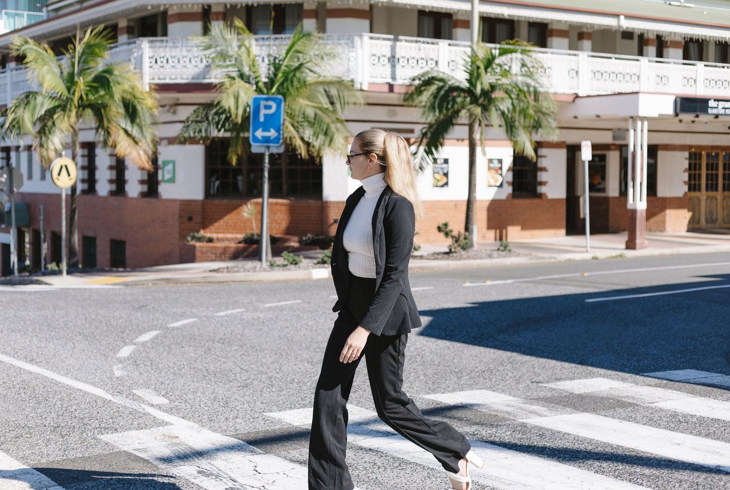 Person in business attire walking through urban street setting.