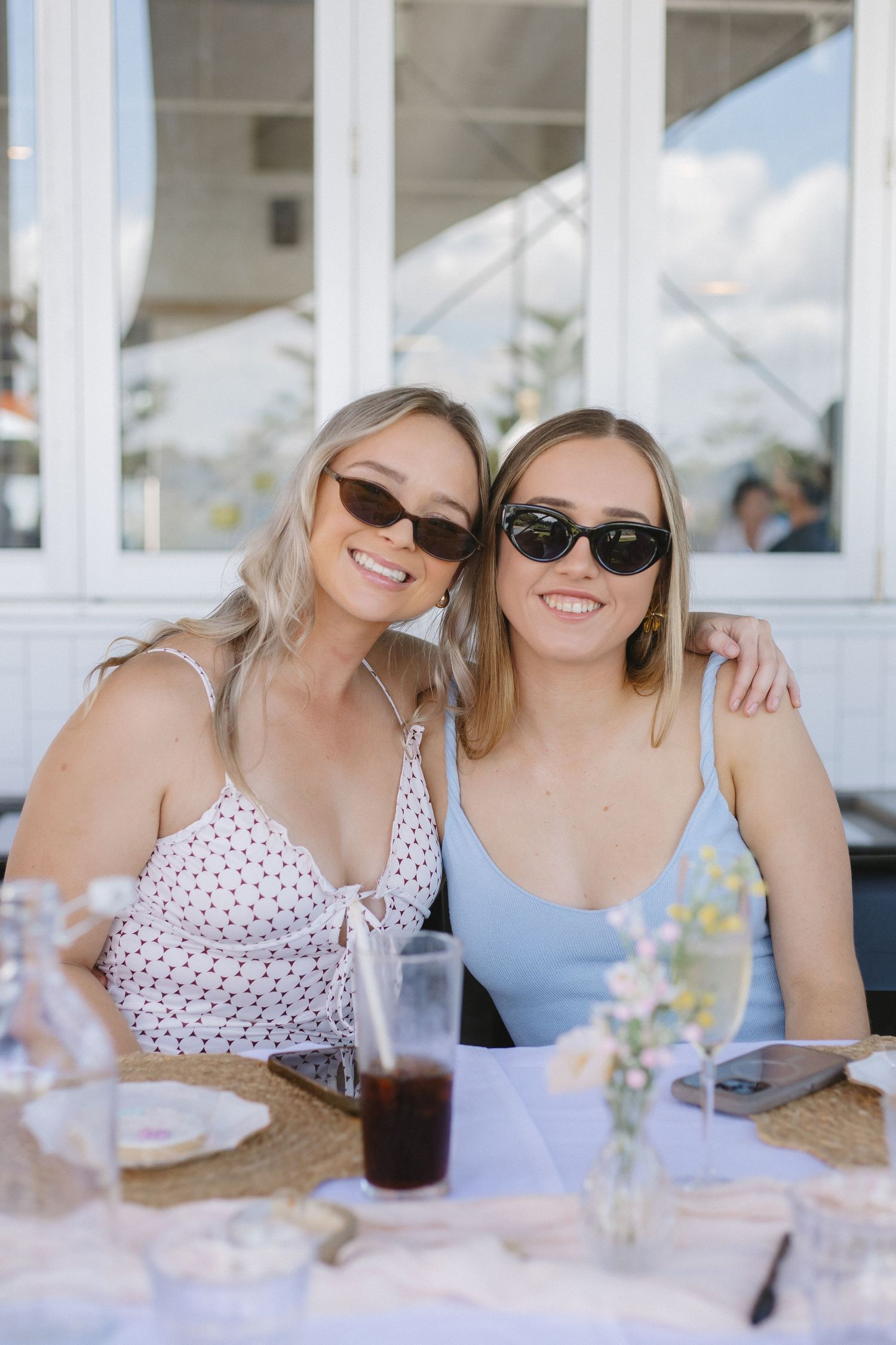 Friends enjoying drinks and conversation at an outdoor restaurant table.