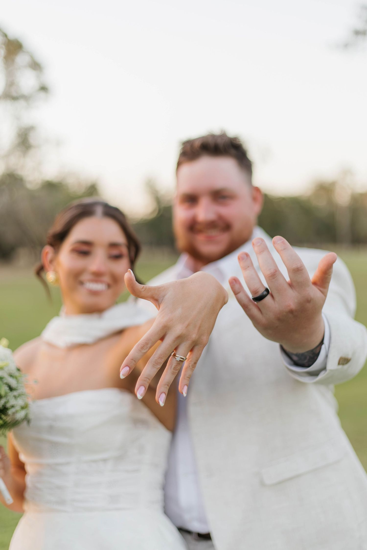 Happy newlyweds showing off their wedding rings with joyful expressions.