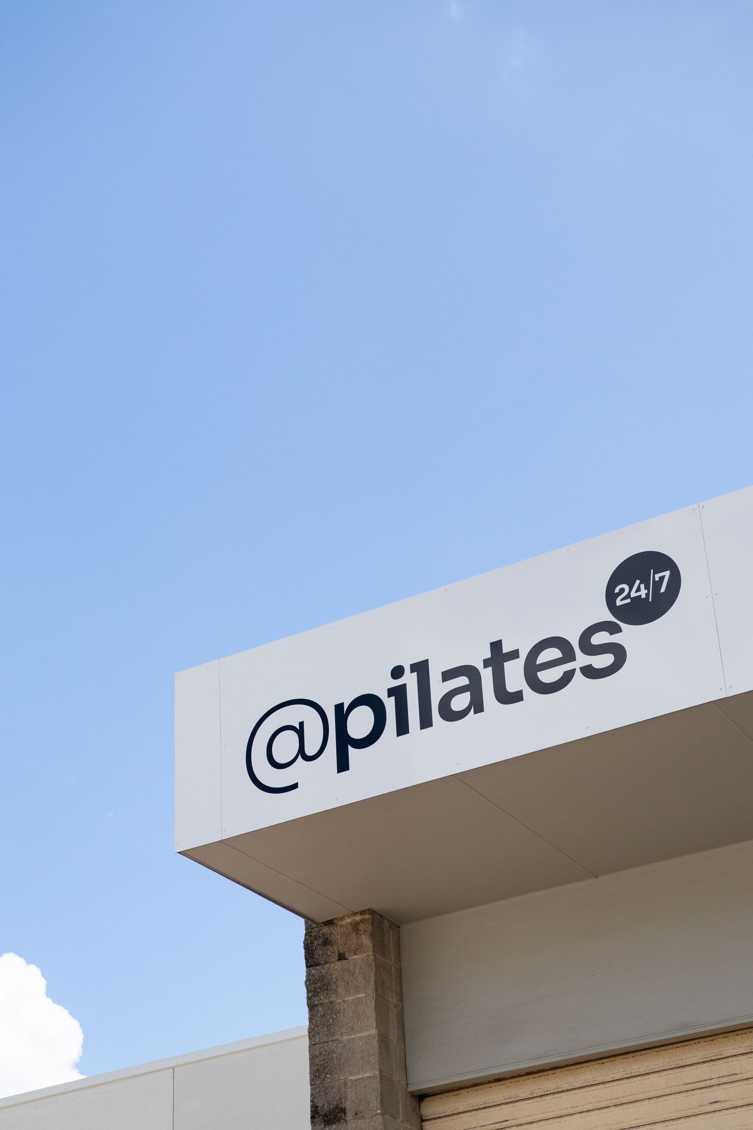 Pilates studio exterior signage against blue sky background.