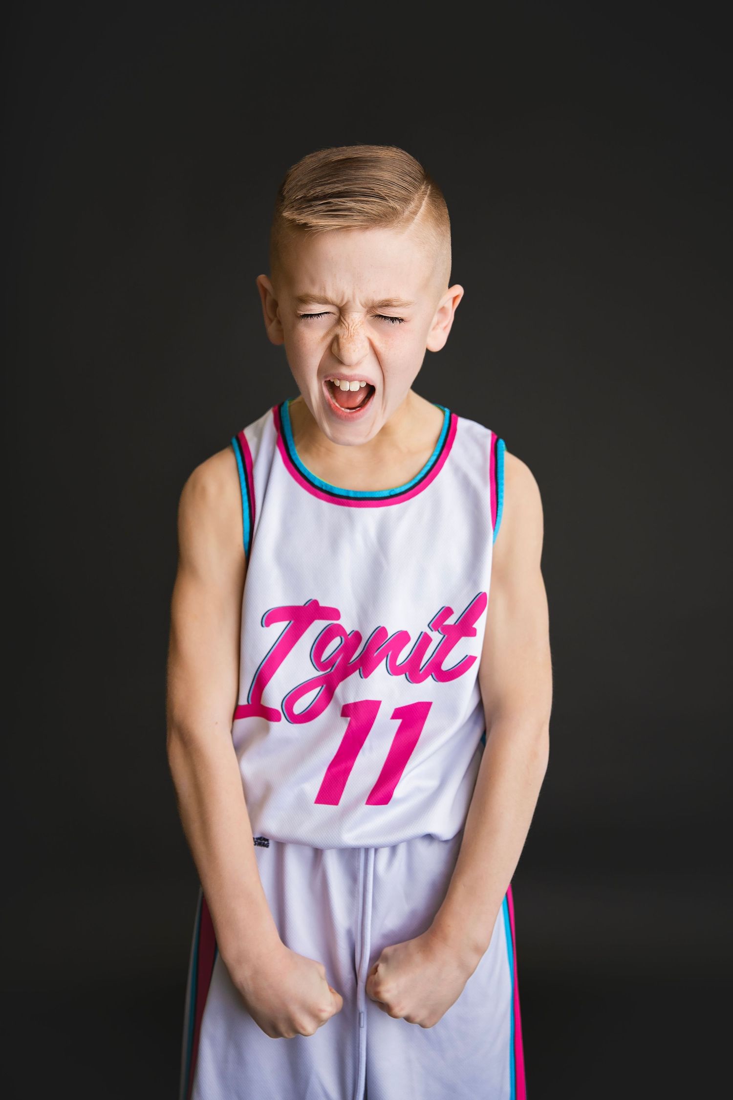 Intense young boy in Ignit number 11 jersey yells with fists clenched.