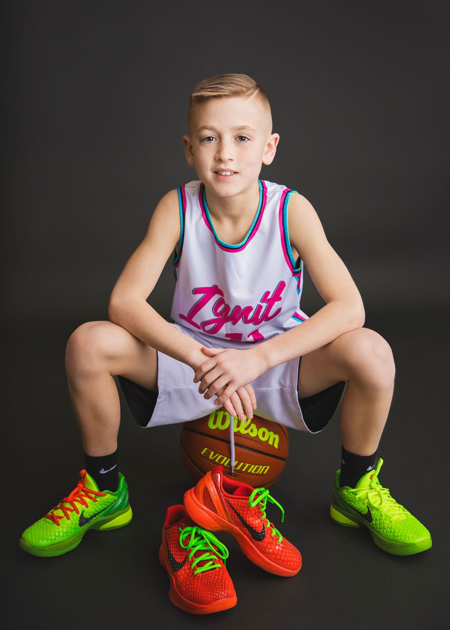 Young boy in Ignit basketball jersey crouches over Wilson Evolution basketball.
