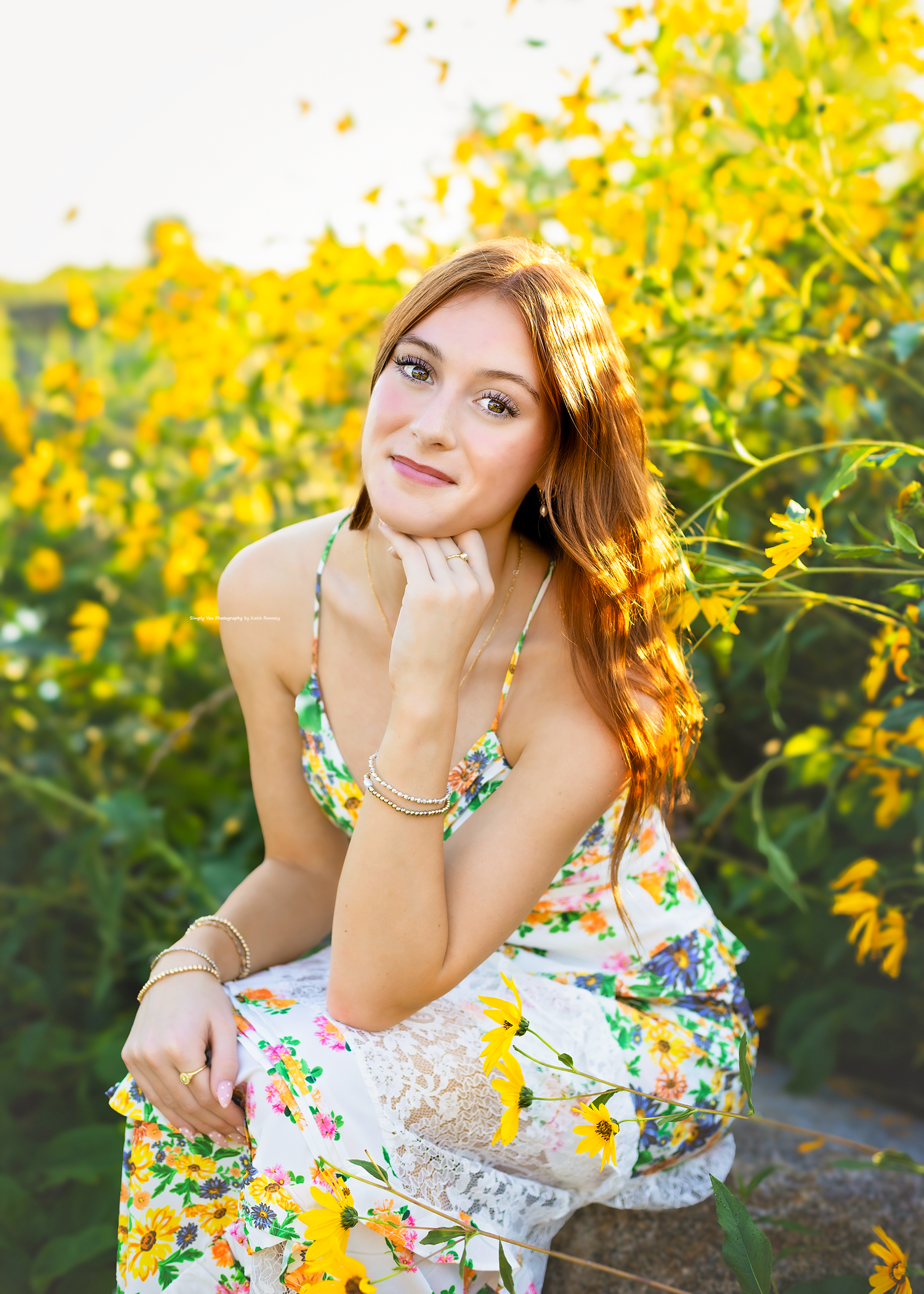 Young woman in floral dress posing among vibrant yellow wildflowers in golden sunlight.