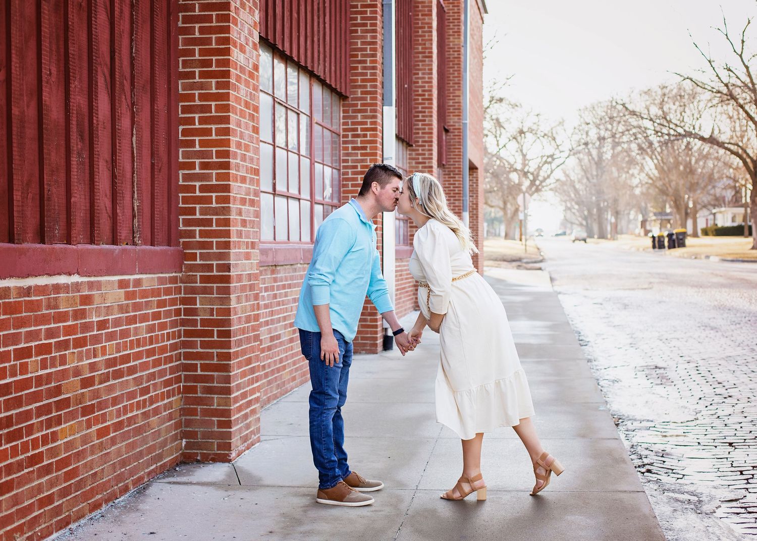 Expecting couple sharing a romantic kiss during outdoor maternity photo session.