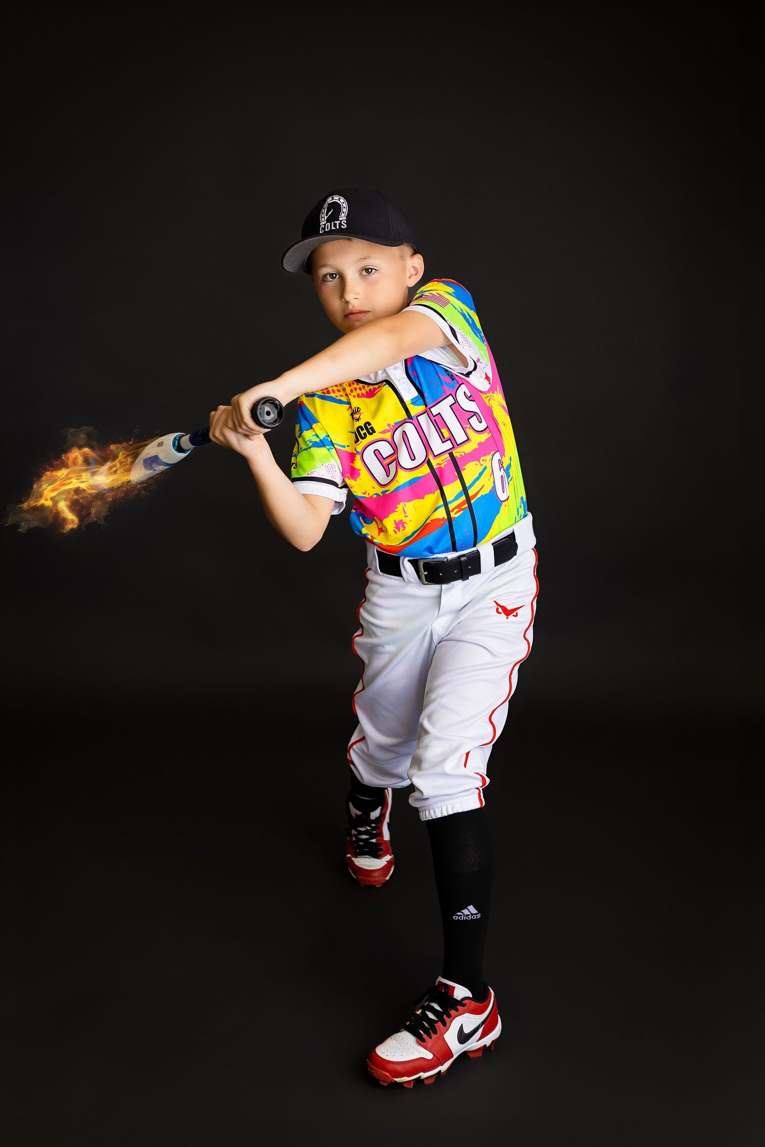 Young baseball player in colorful Colts jersey swings bat with flame effect in dramatic team photo.