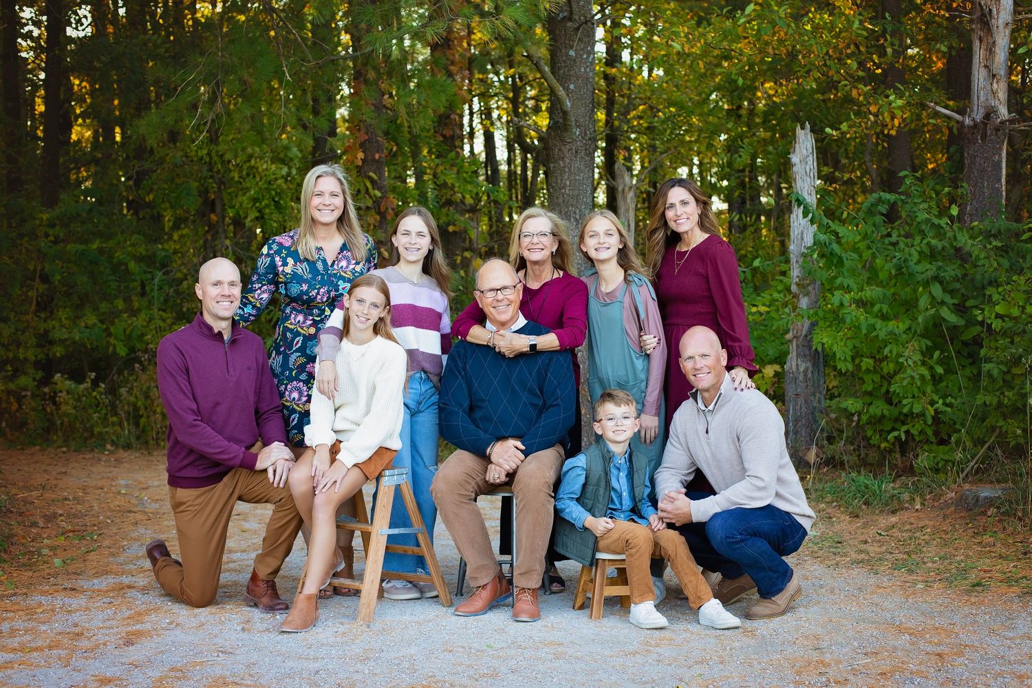 Extended family of ten posing together in an autumn forest setting.