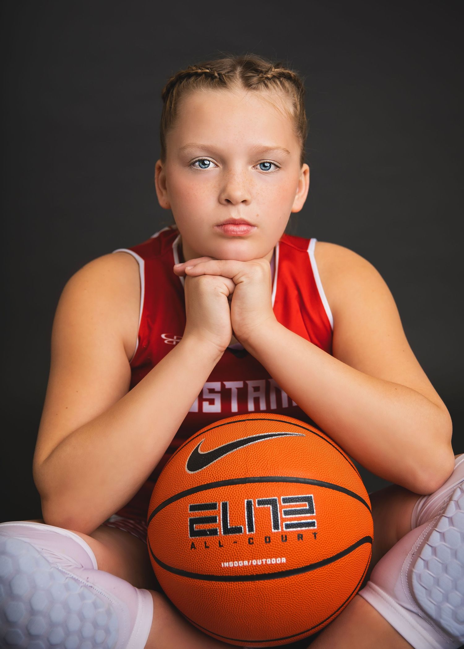 Young athlete in Mustangs jersey rests chin on hands over a Nike Elite basketball.