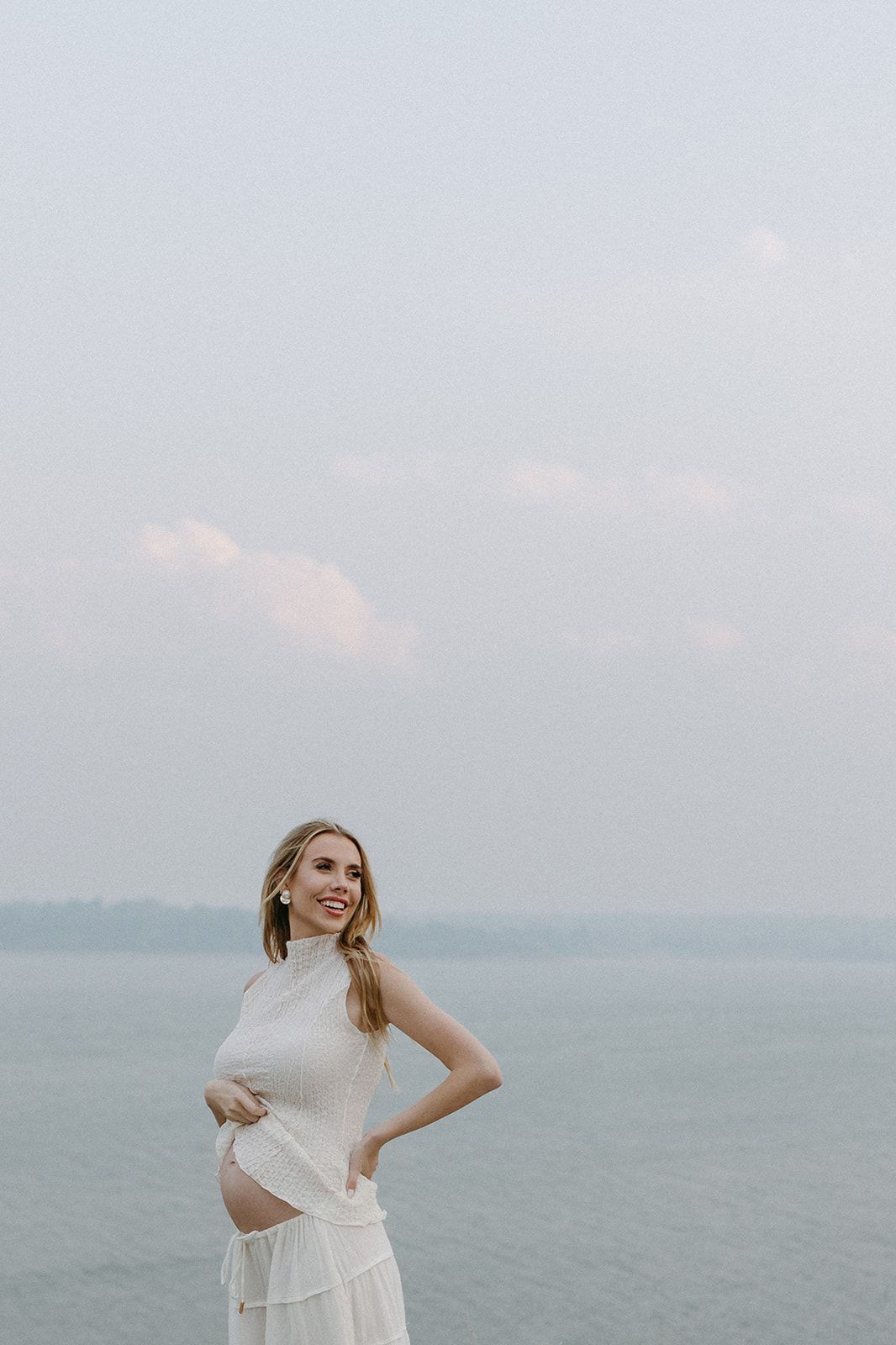 Woman in white dress dancing on a misty beach.