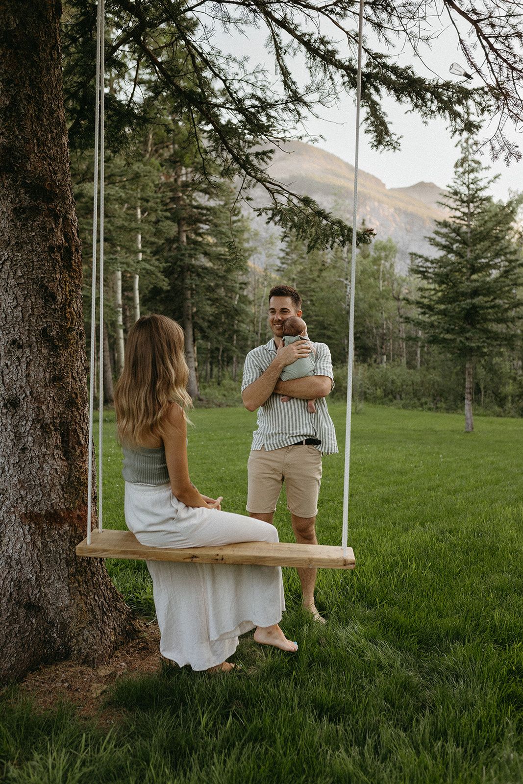 Couple enjoying time together on wooden swing in mountain forest setting.