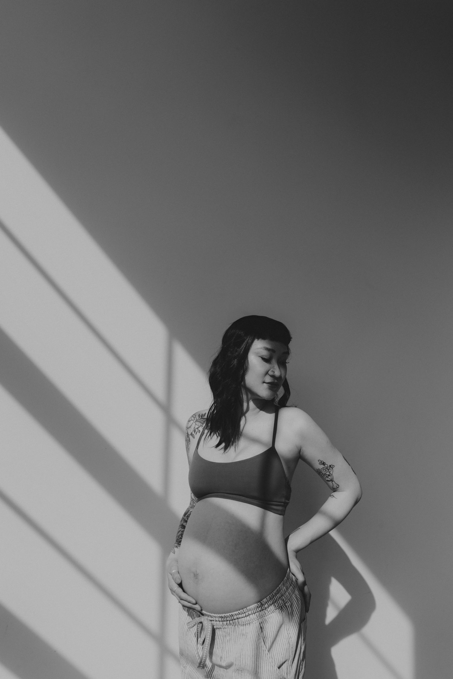 Dramatic black and white maternity portrait with angular shadows.