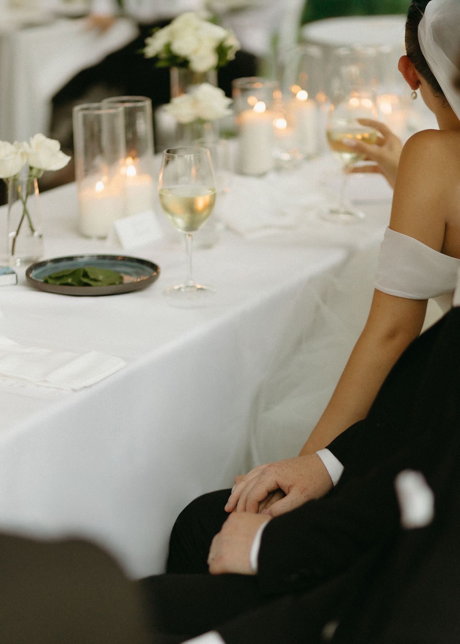 Elegant wedding table setting with white linens, candles and floral arrangements.