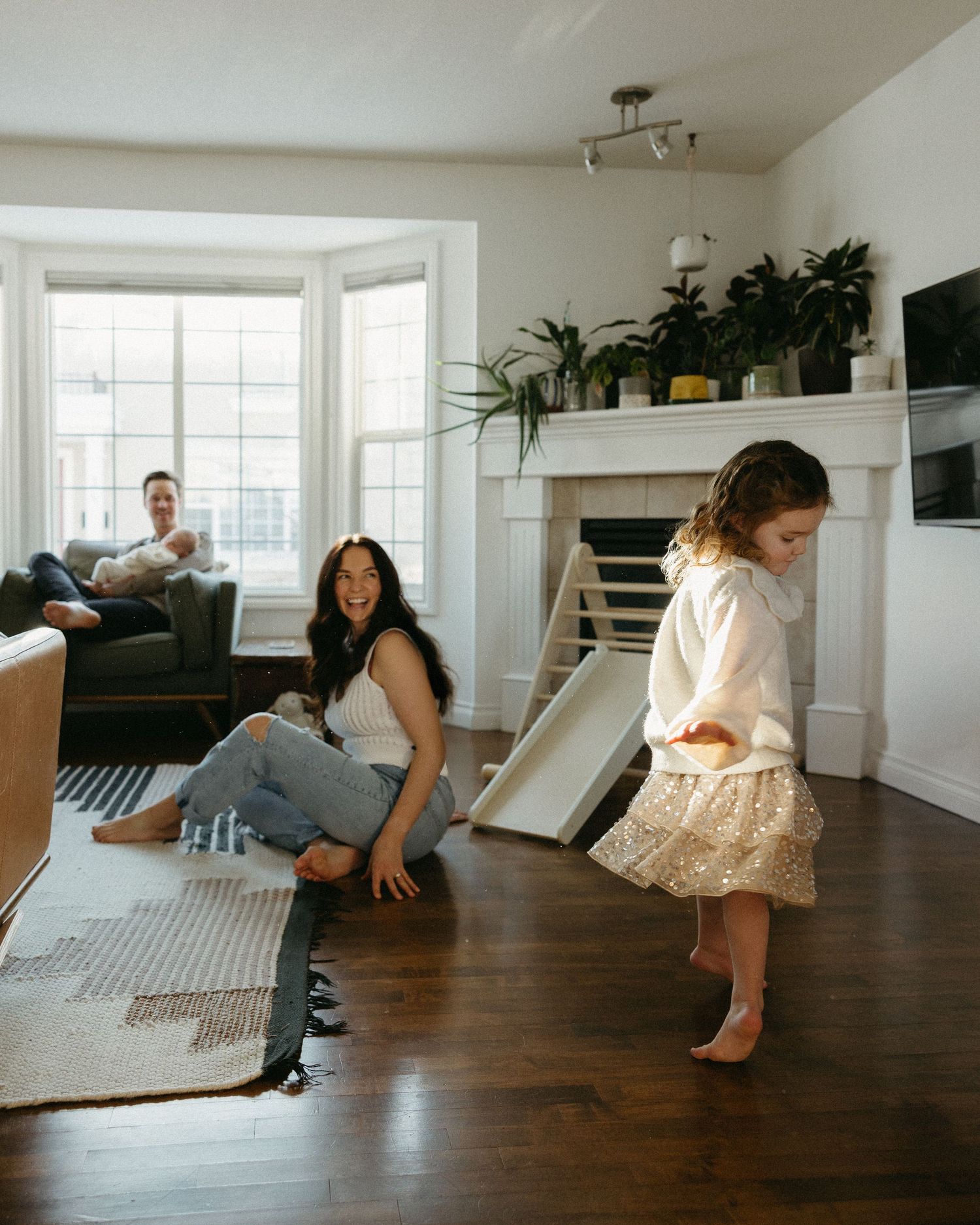 A sequence of candid family moments captured on a hardwood floor in a bright living room.