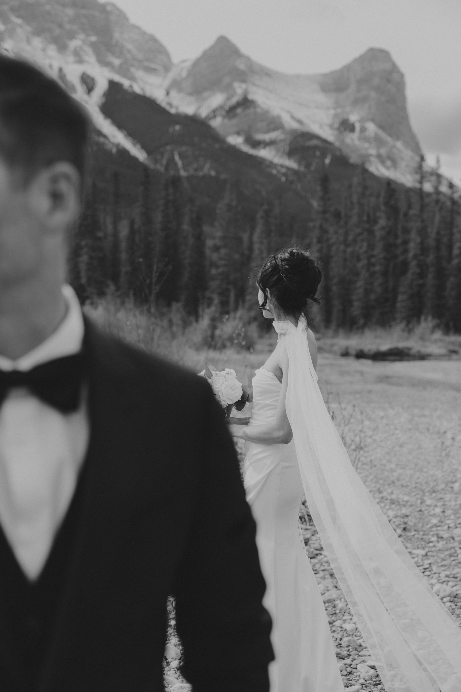 Wedding couple in black and white against dramatic mountain landscape.