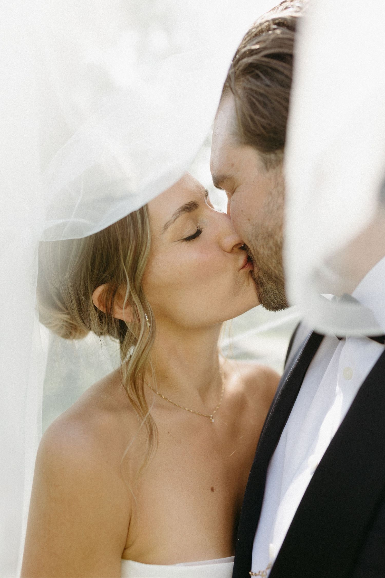 Romantic black and white wedding portrait showing tender kiss between newlyweds.
