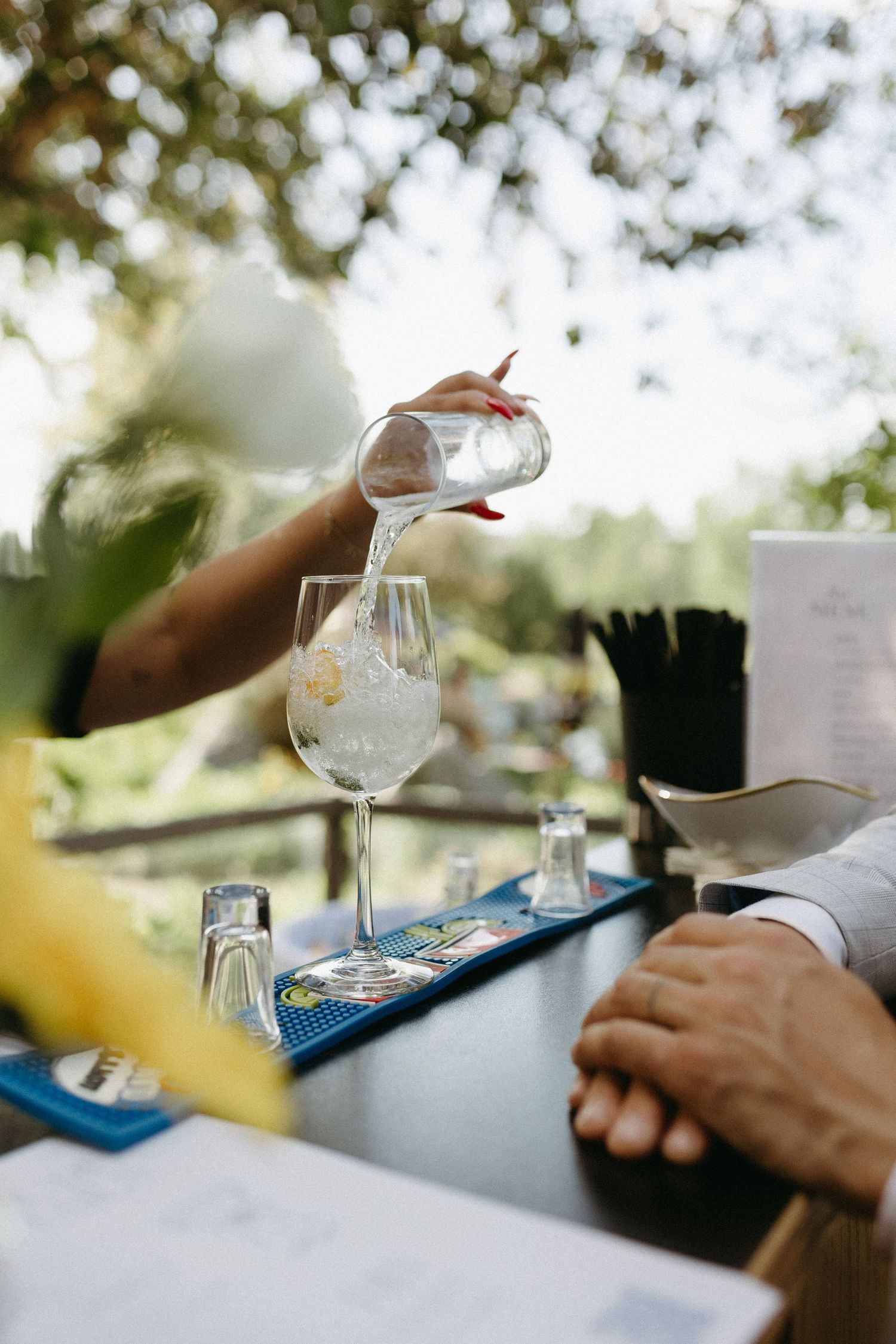 Wine glasses and place settings arranged on an outdoor table during a wedding reception.