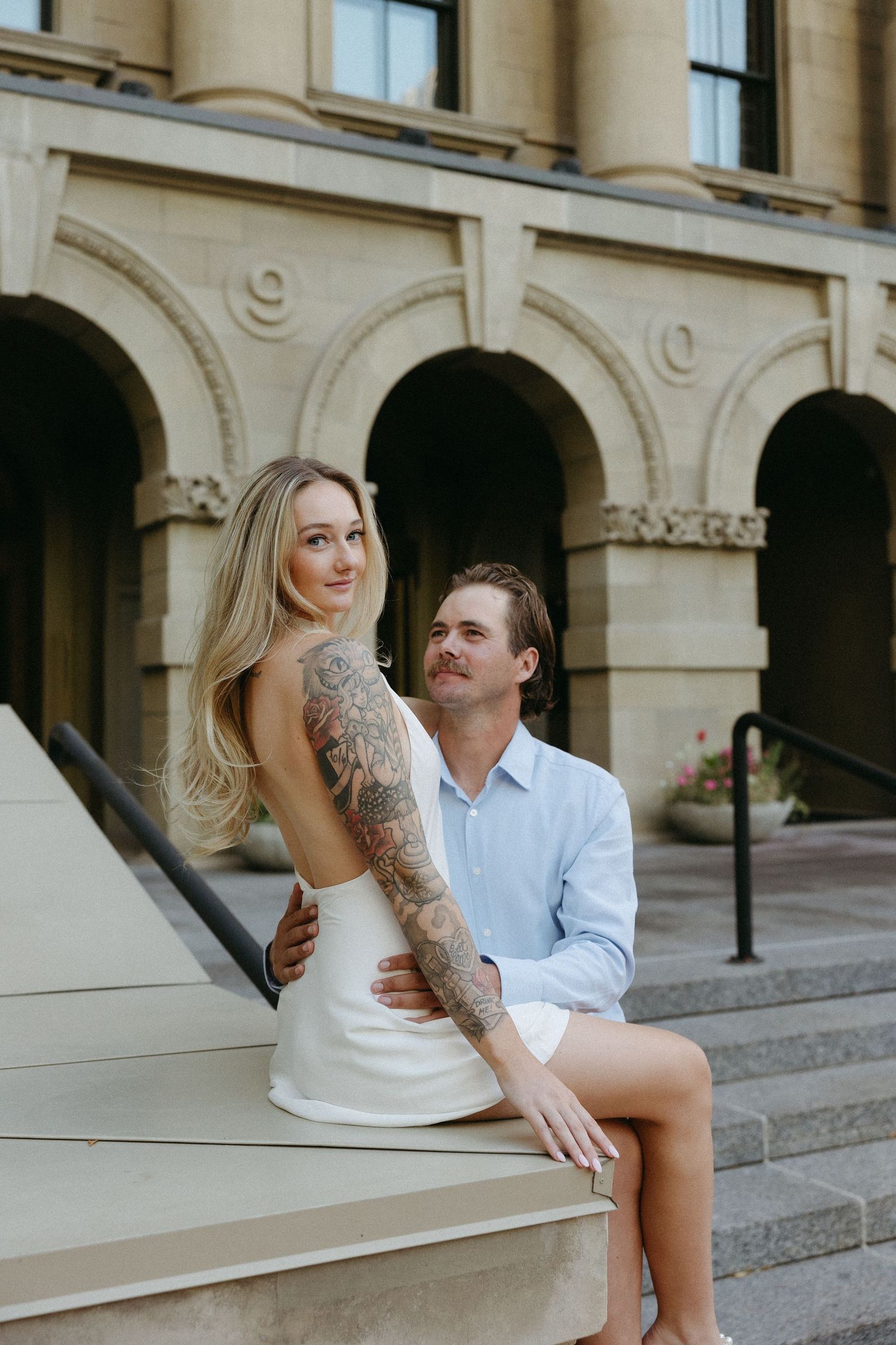 Intimate moment shared on stone steps of a historic building with elegant architectural details.