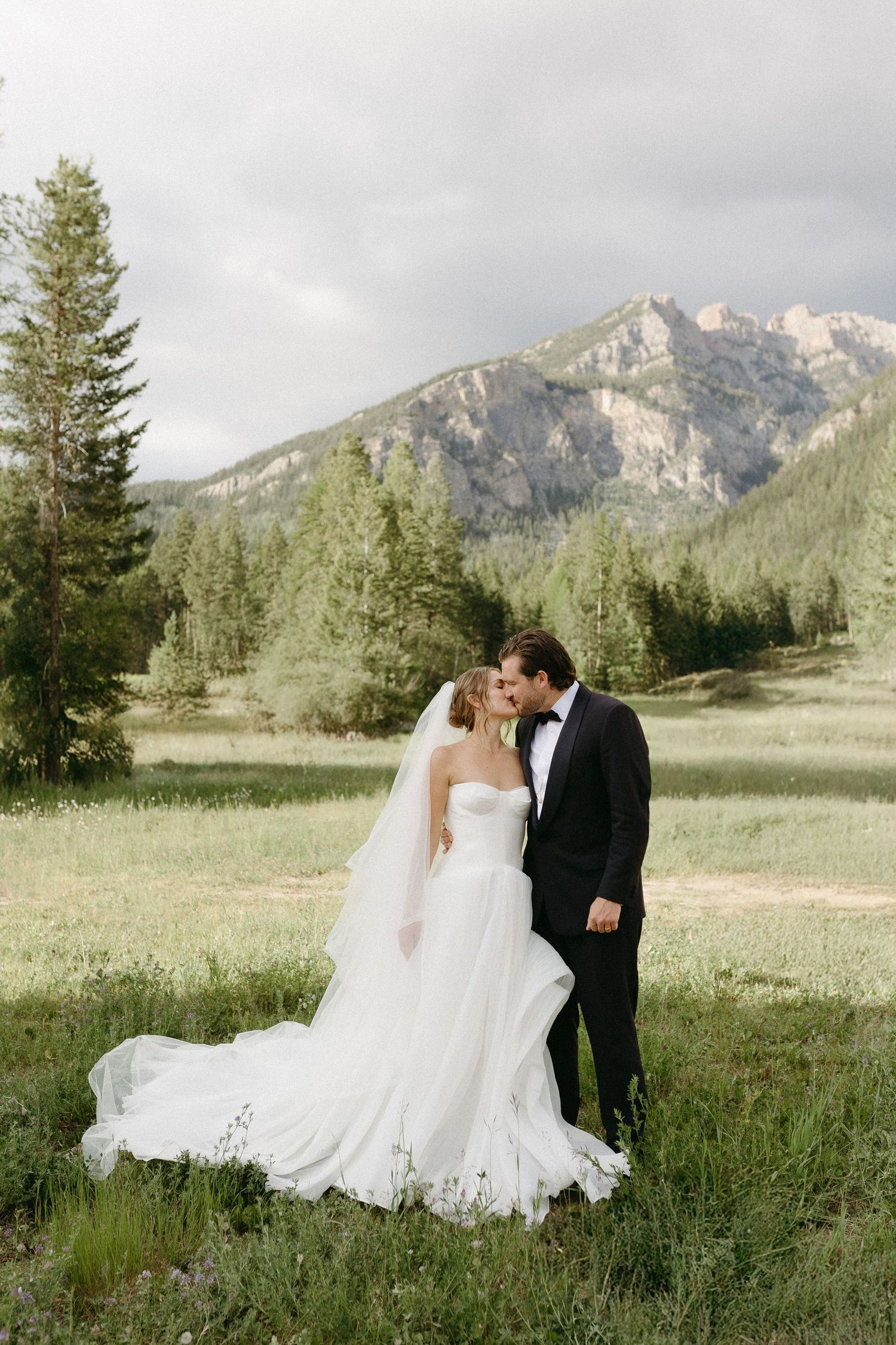 Wedding photos in a mountain meadow with dramatic peaks in background.