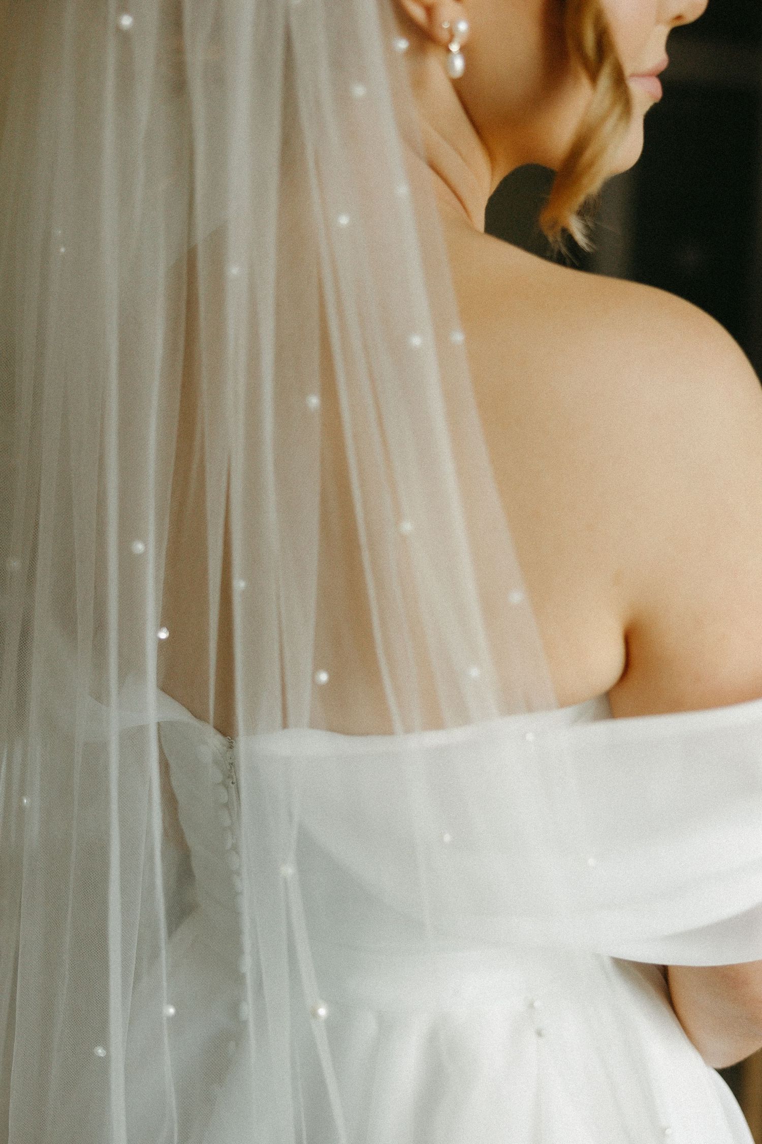 Close-up detail of a bride's white wedding dress and veil with delicate sparkles.