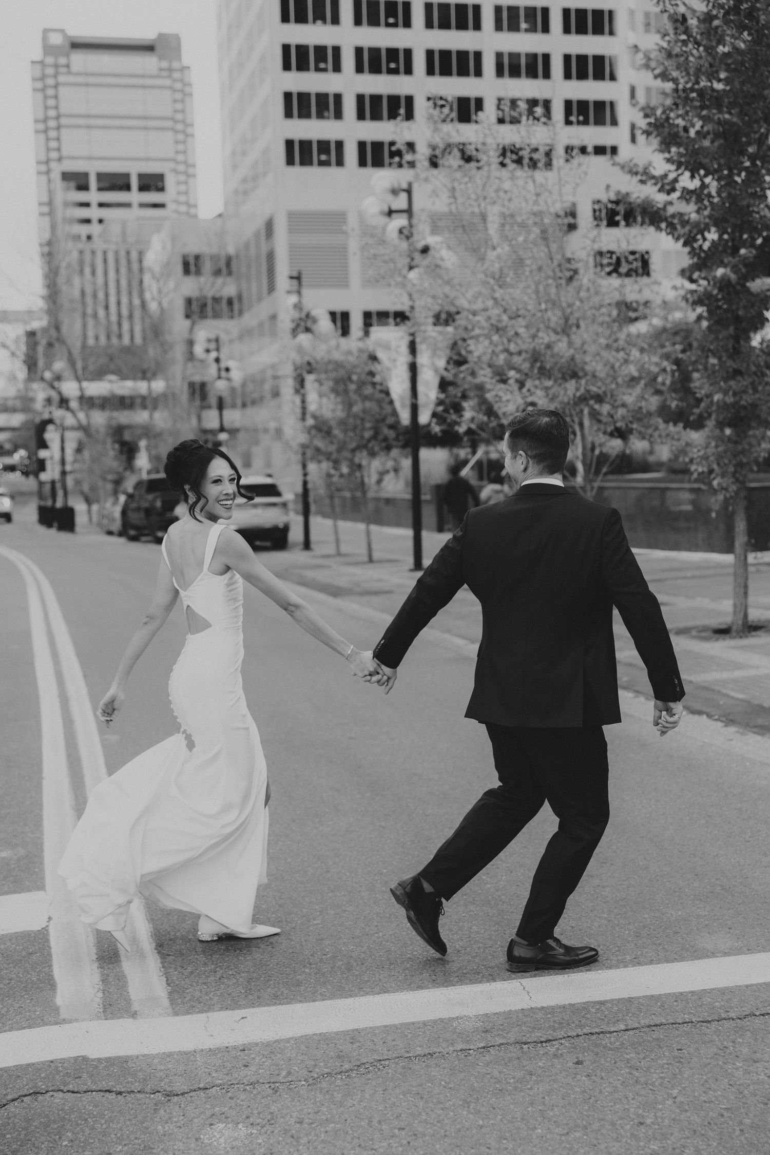 Playful black and white photos of newlyweds dancing in urban setting.