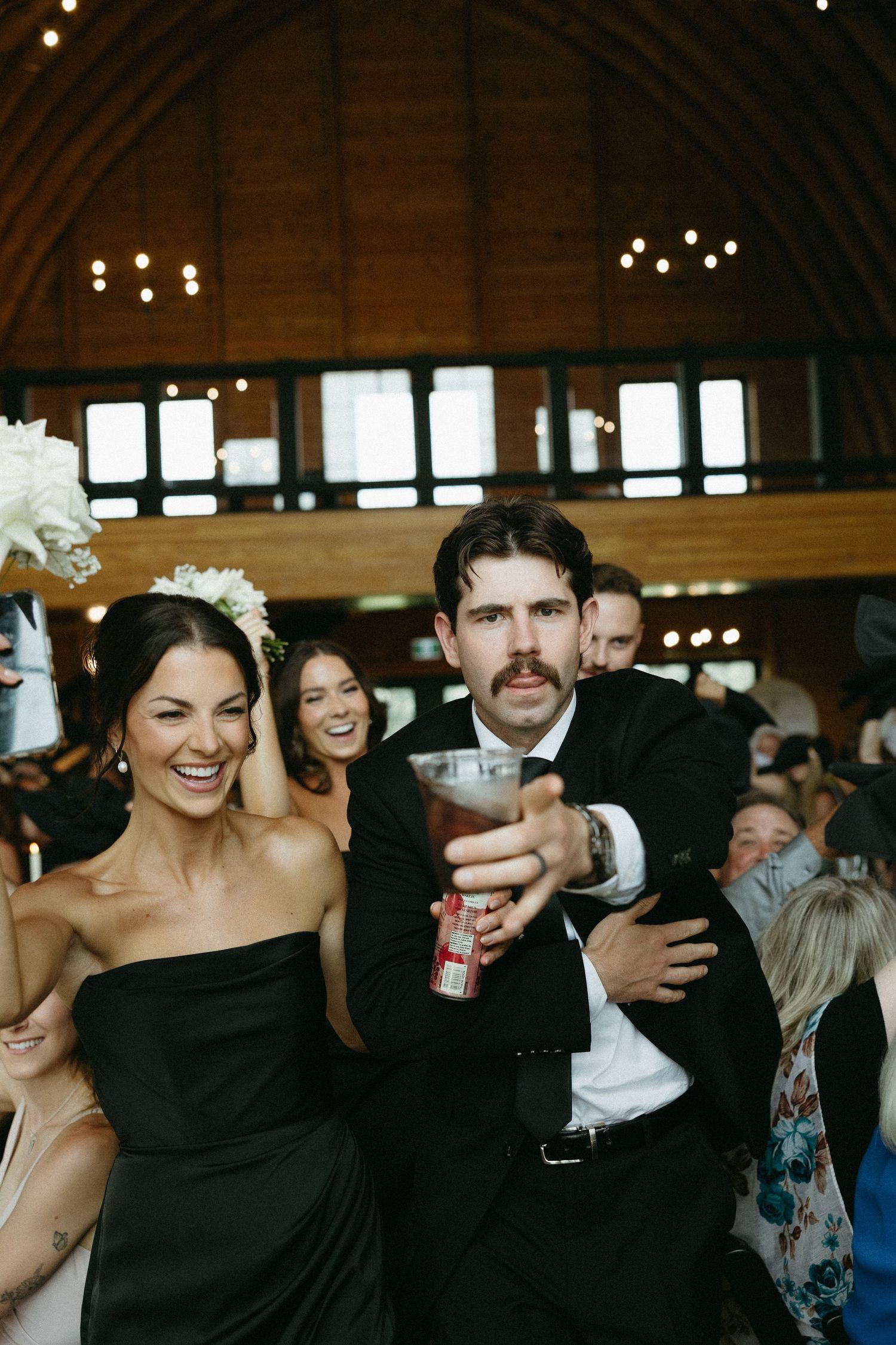 Wedding reception celebration in rustic wooden venue with string lights.