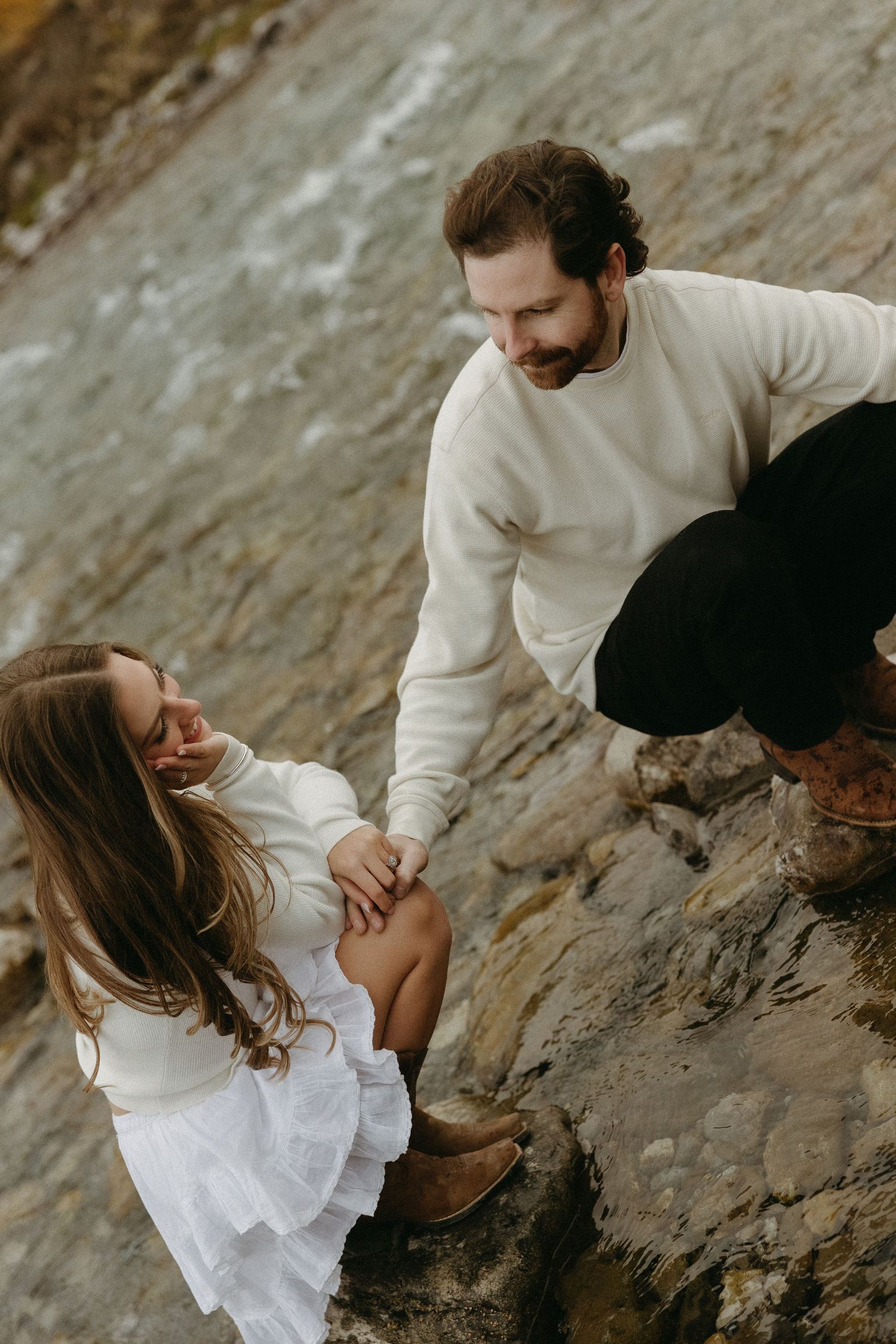 Couple sharing intimate moments on rocky coastal cliffs.