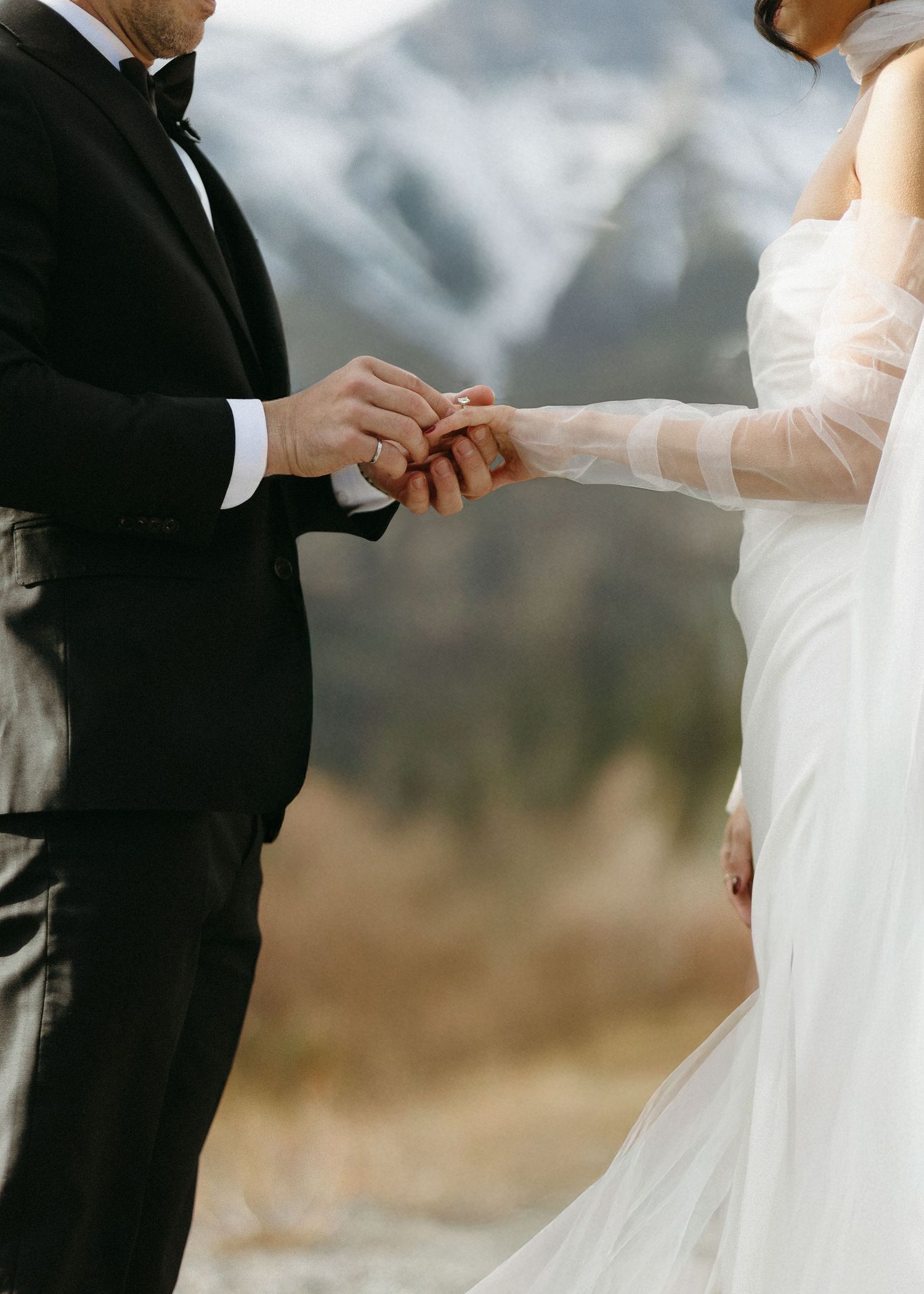 Intimate wedding ceremony moment with couple exchanging rings outdoors.