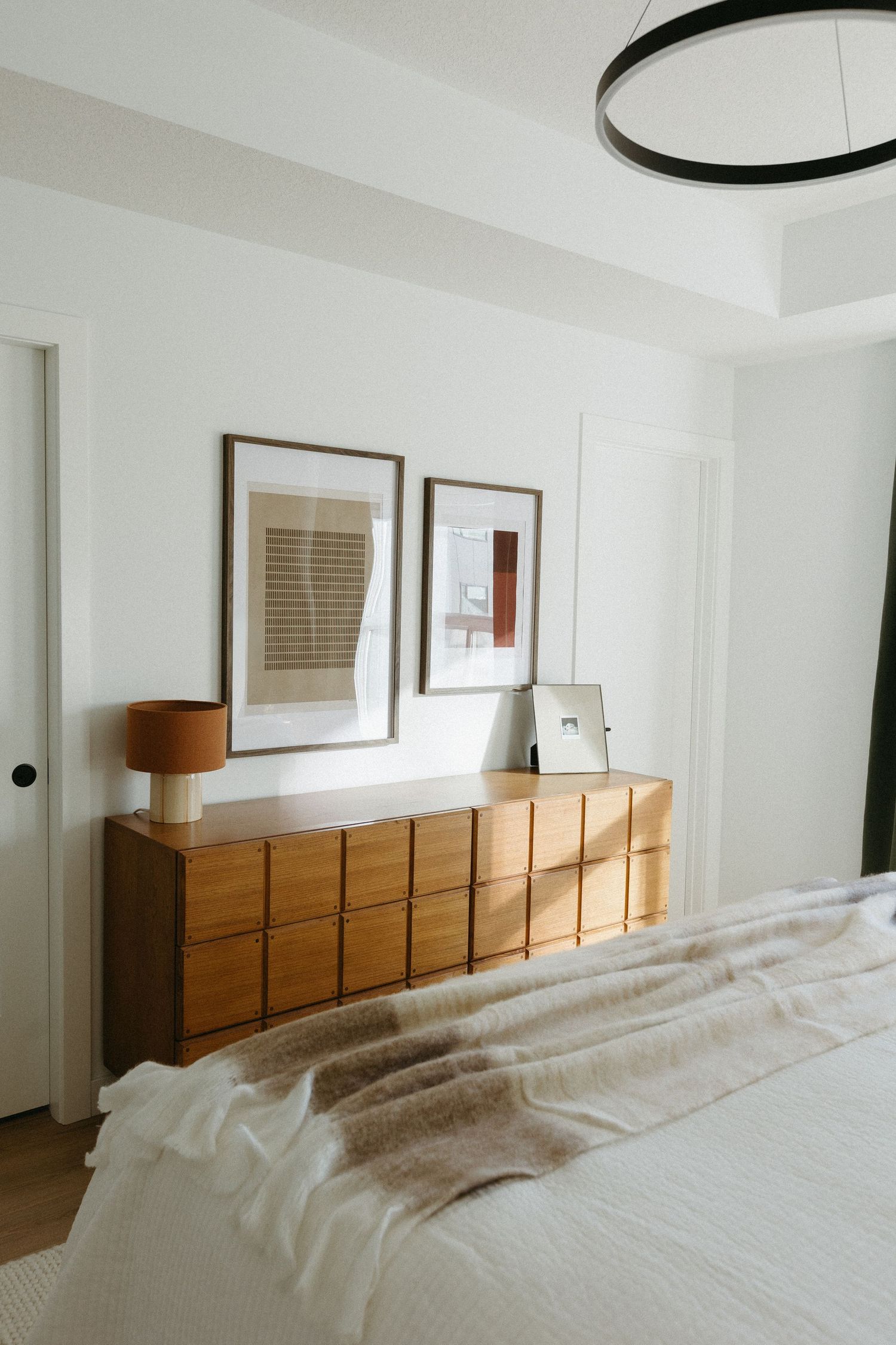 Modern bedroom with wooden headboard storage and clean white bedding.