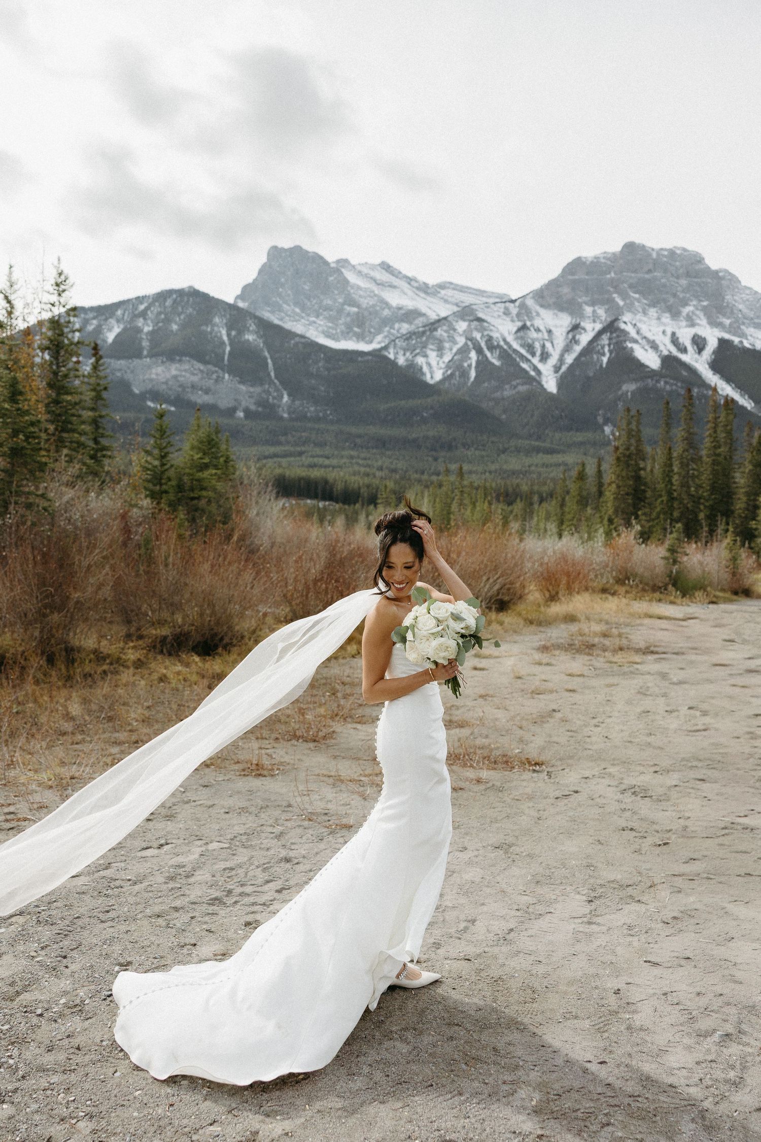 Elegant bridal portraits with flowing veil against mountain scenery.