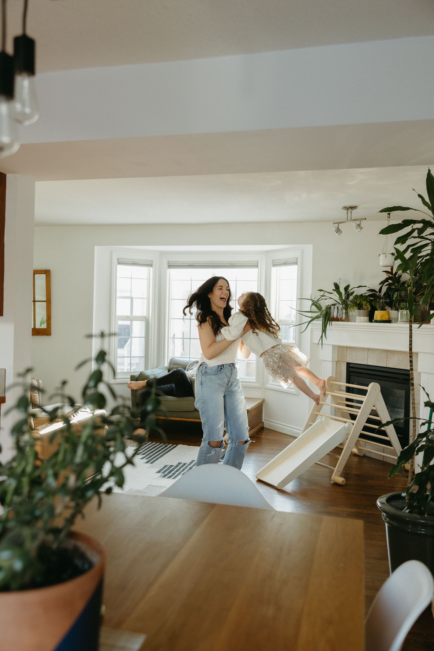 A series of candid family interactions in a modern living room with large windows.
