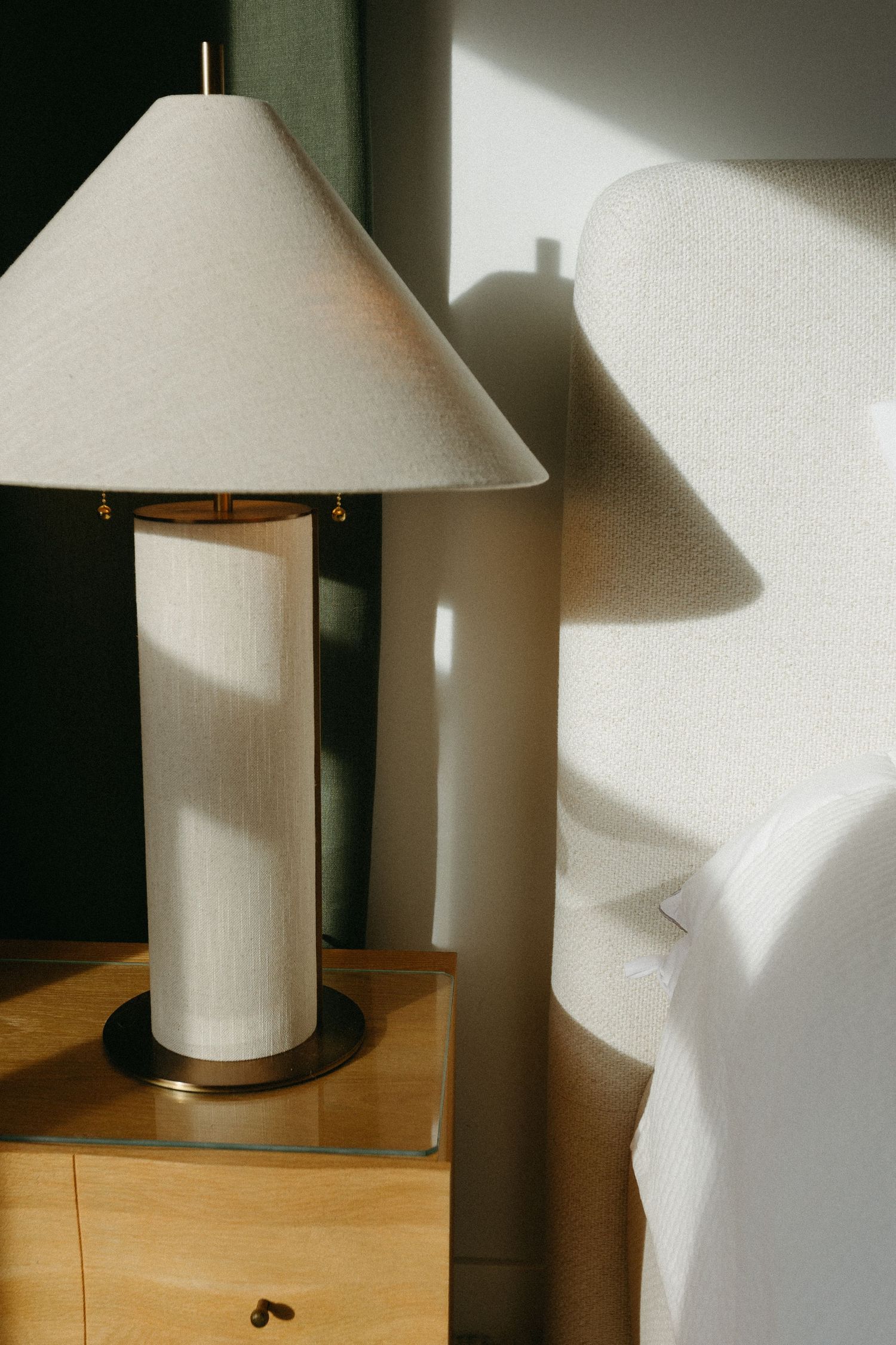 White table lamp with cylindrical shade creating dramatic shadows in a dark room.