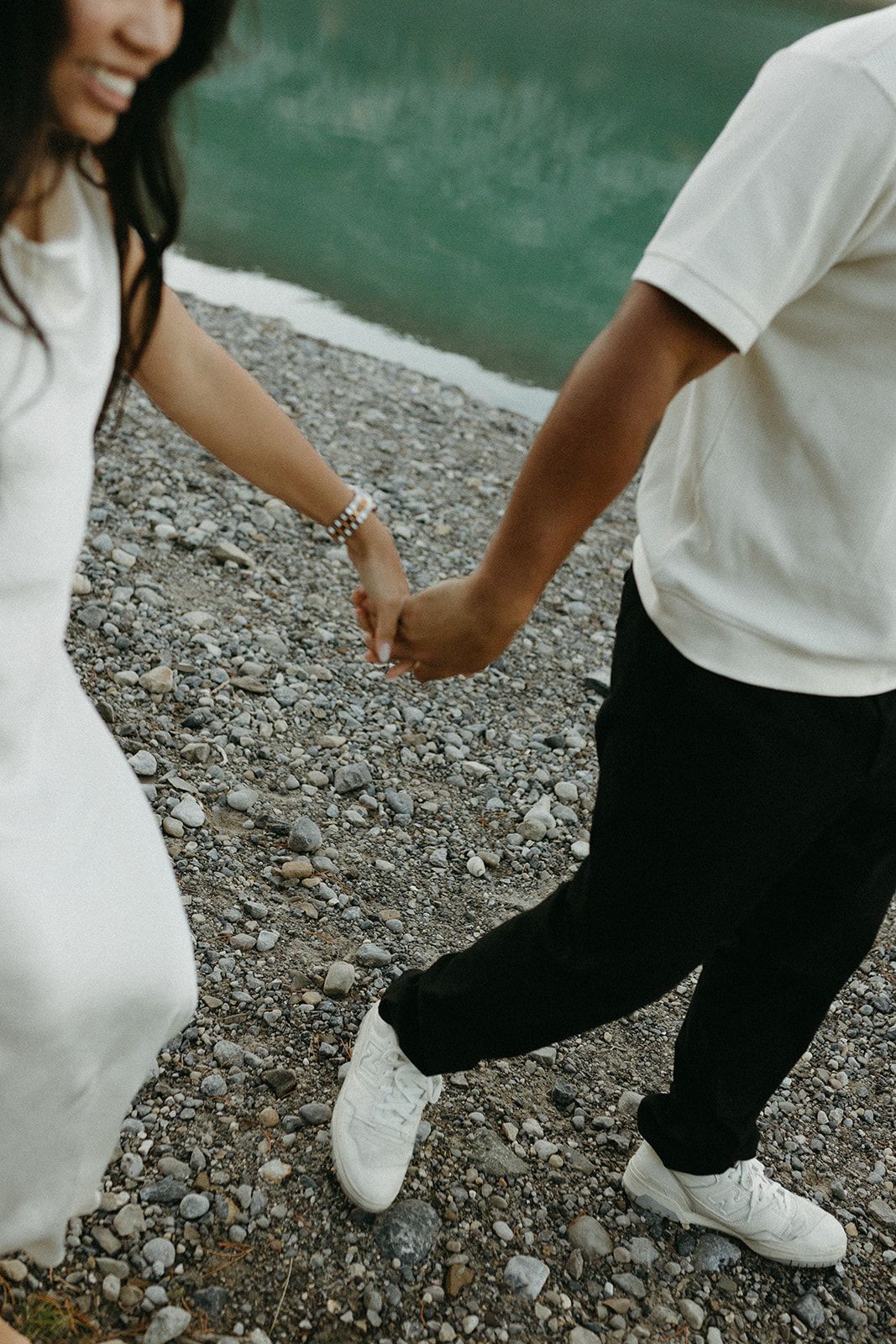 Close-up of feet in white shoes walking on rocky ground.