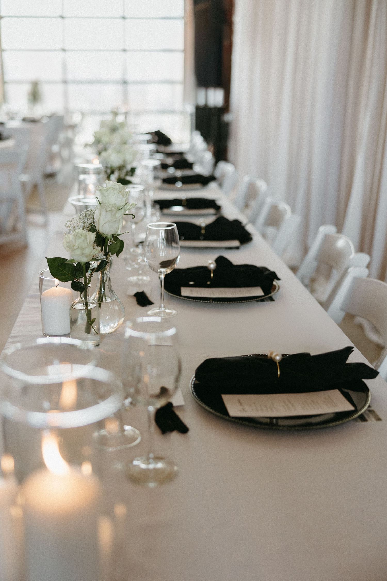 Elegant black and white table settings with candles and floral centerpieces.