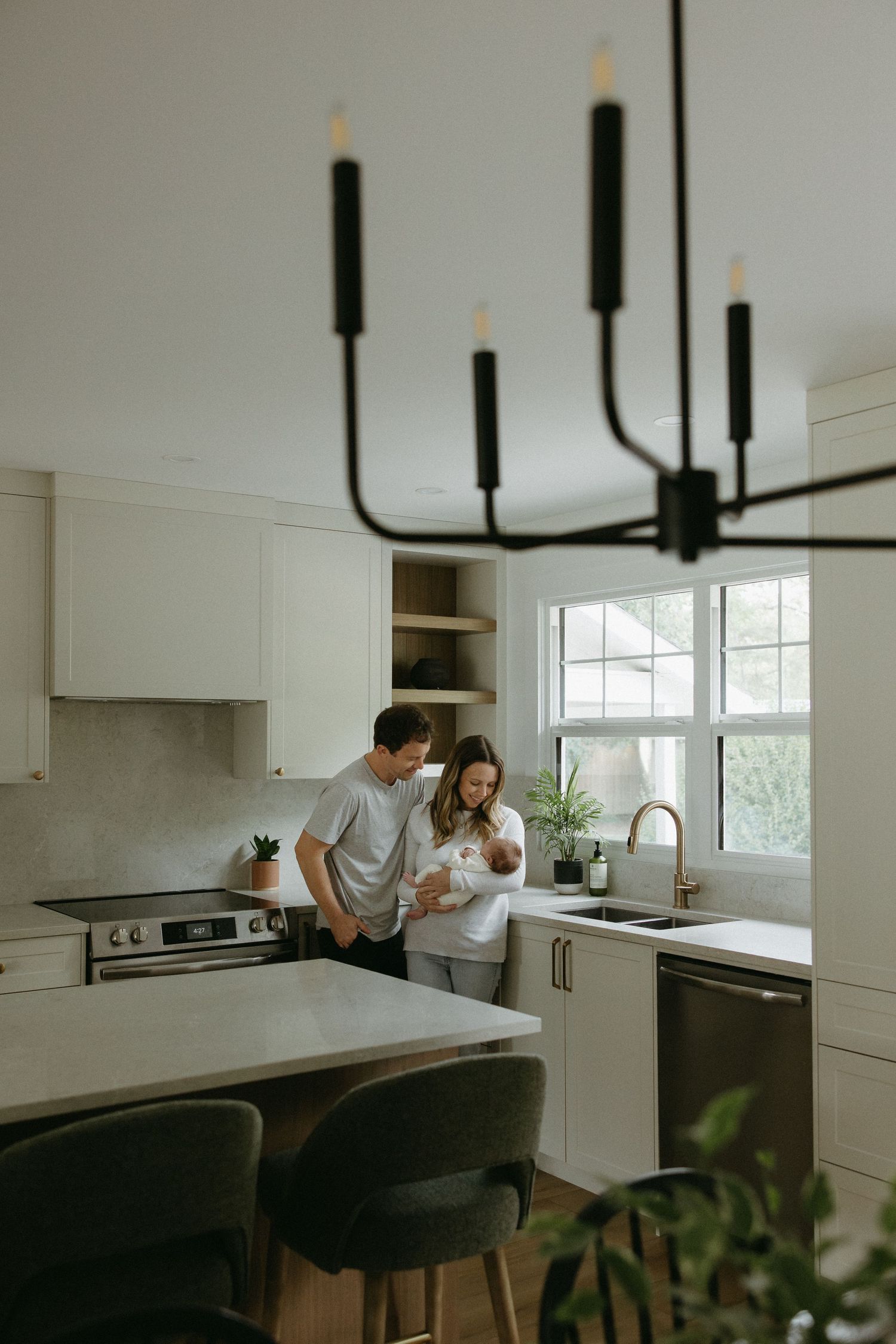 Modern white kitchen interior with pendant lights and family gathering at counter.
