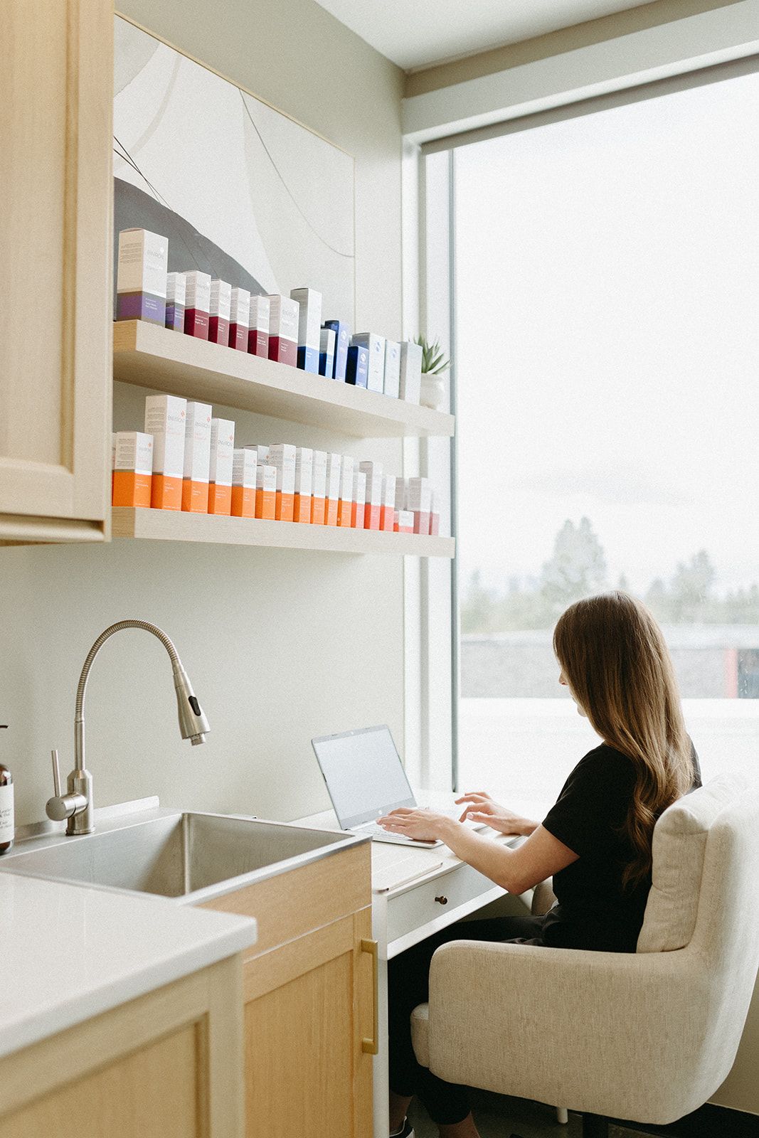 Modern white office workspace with bookshelves and window views.
