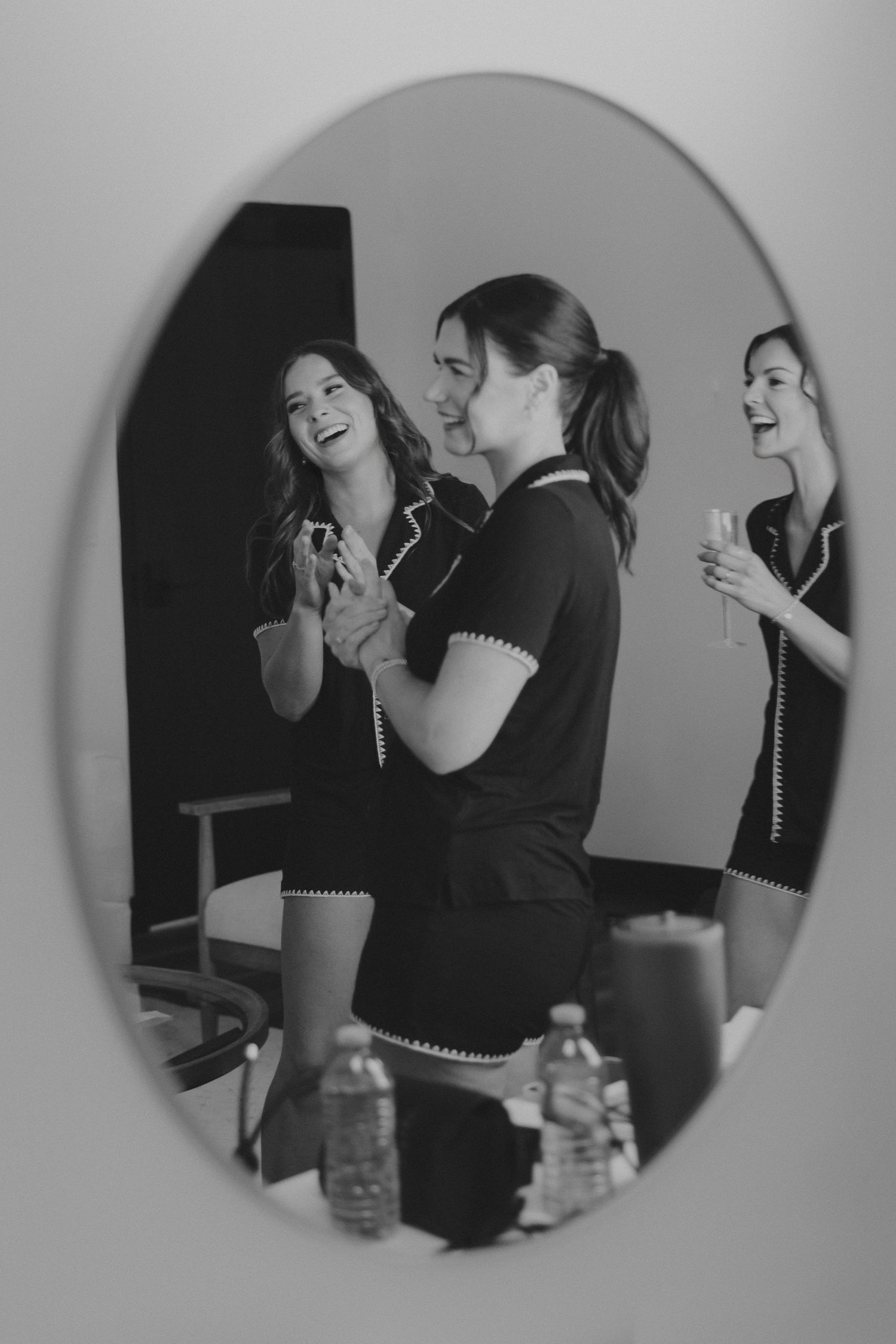 Joyful moments captured in an oval mirror reflection showing people in black outfits laughing together.