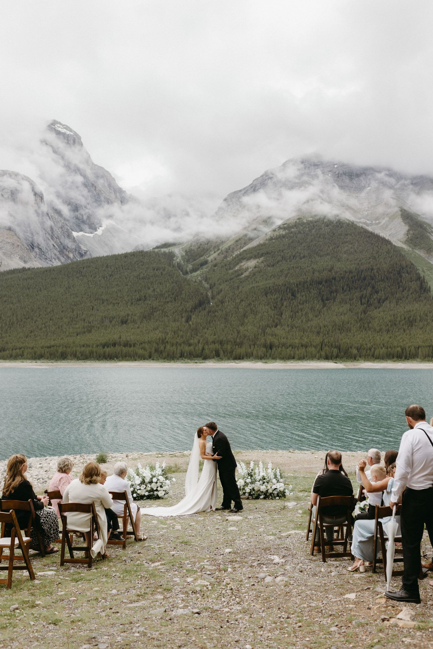 Mountain lakeside wedding ceremony setup with chairs facing dramatic alpine views.