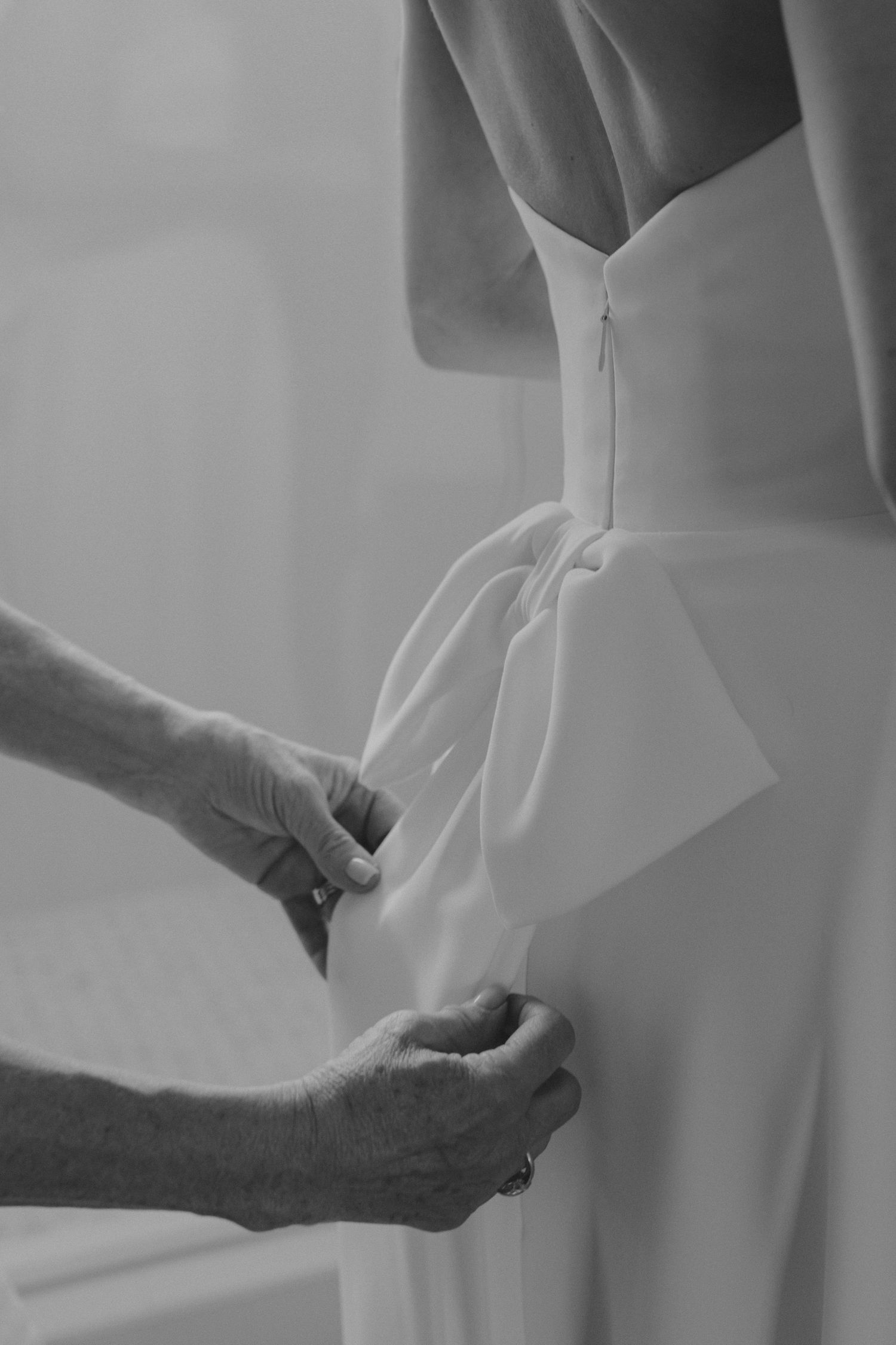 Black and white detail shot of hands adjusting wedding dress.