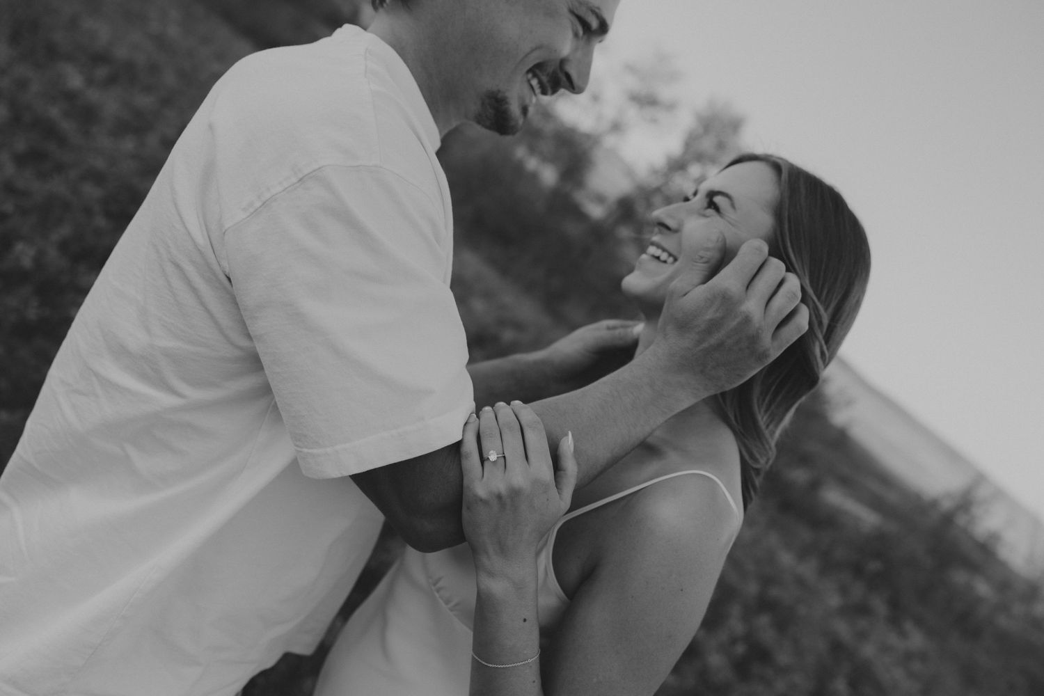 Intimate black and white portrait of couple sharing tender moment outdoors.