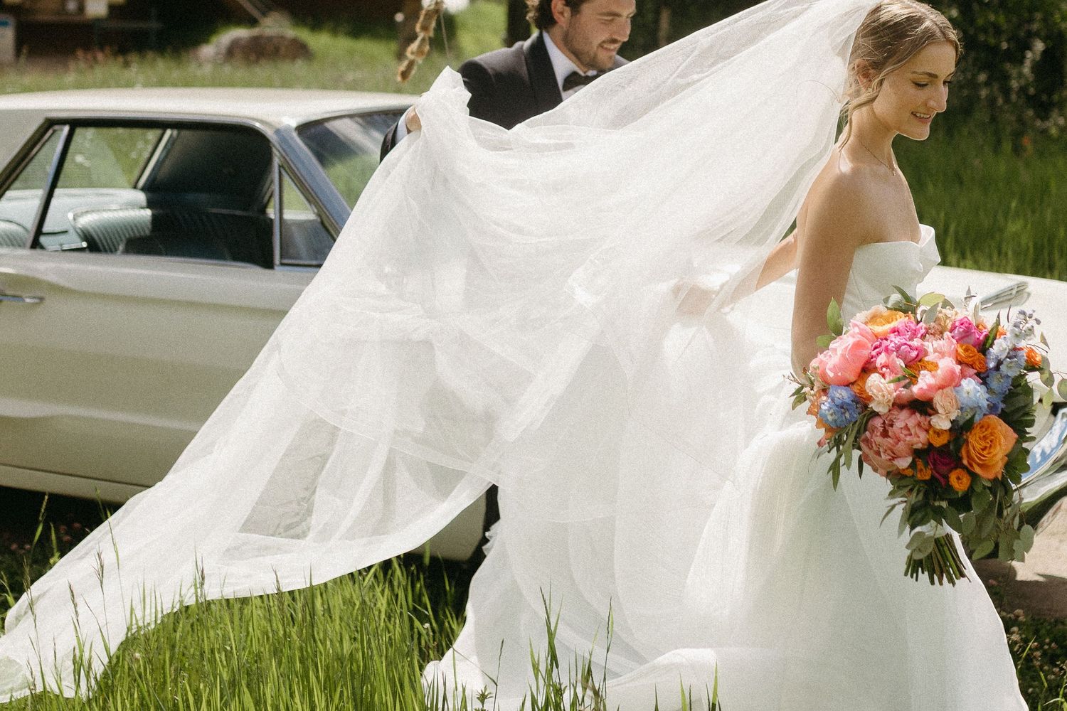 Bride in flowing white dress twirling in an outdoor garden setting.