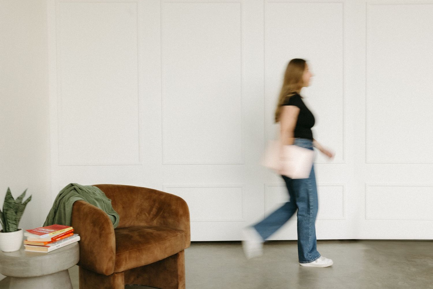 Minimalist white interior space with a brown velvet armchair against a blank wall.