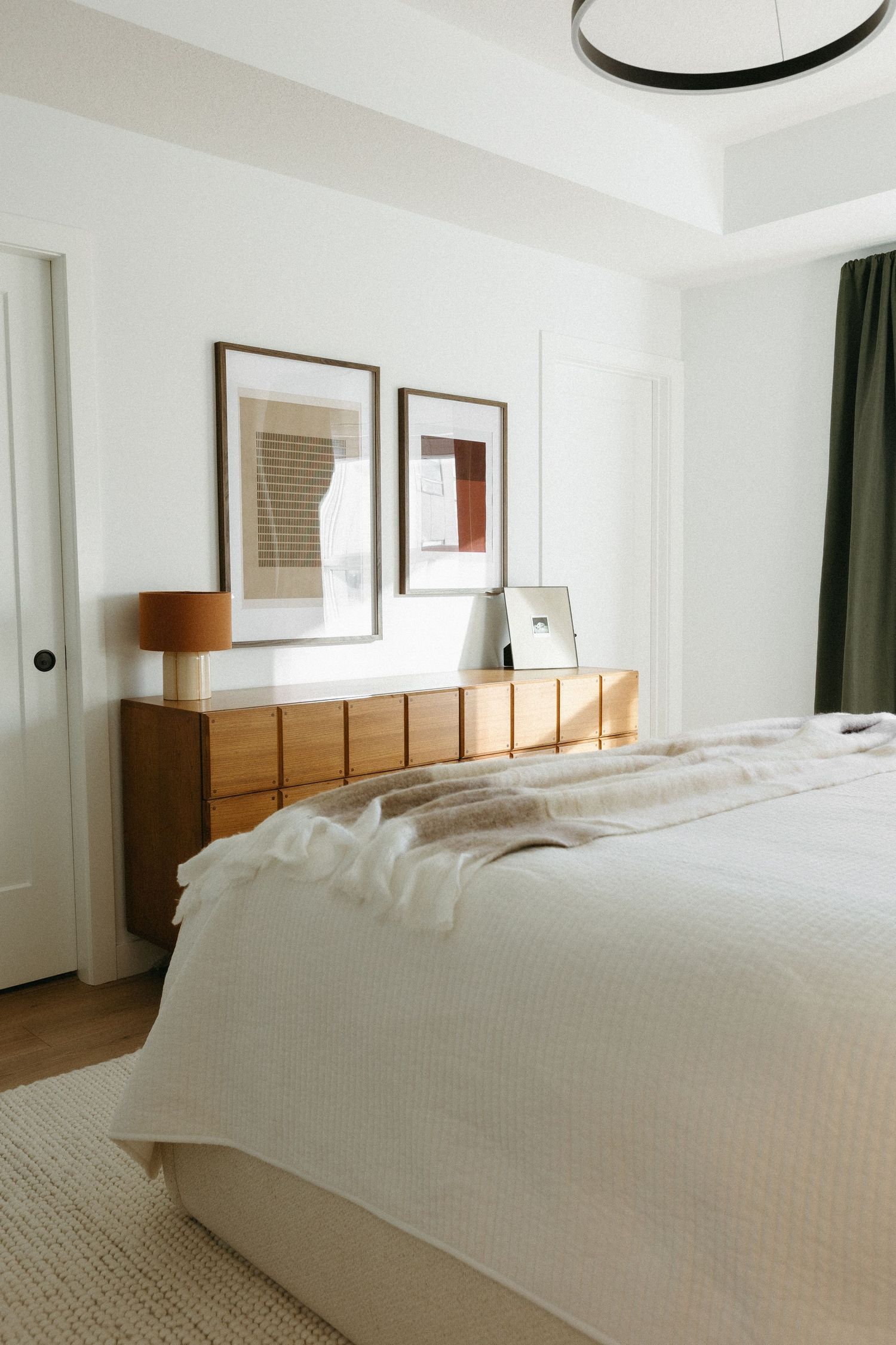 Serene bedroom interior with white walls, wooden furniture and natural light.
